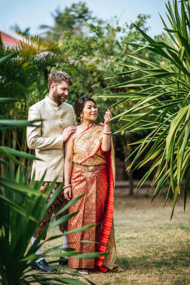 asiatische braut und kaukasischer bräutigam haben romantische zeit mit thailandkleid foto