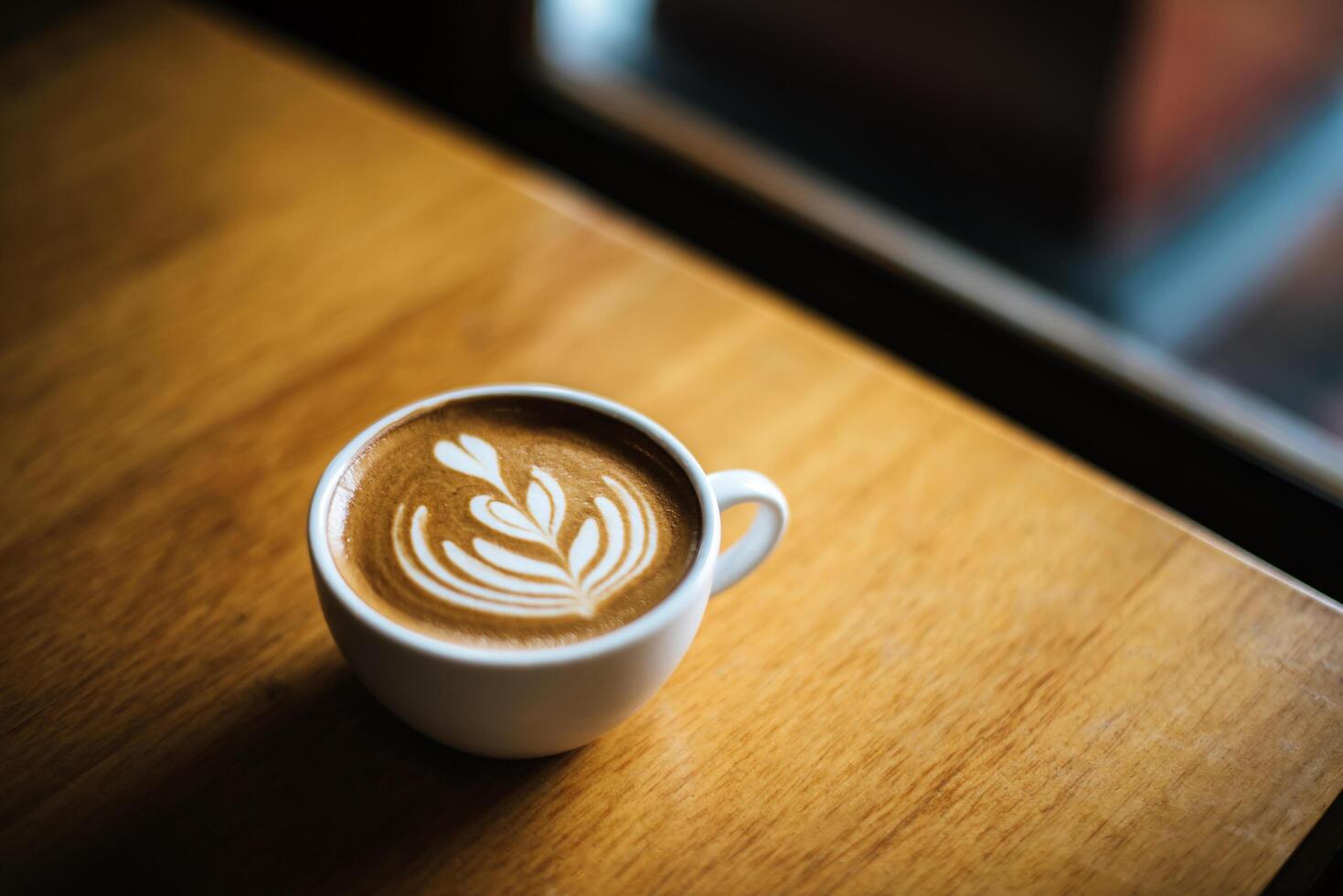Latte Art in Kaffeetasse auf dem Cafétisch foto