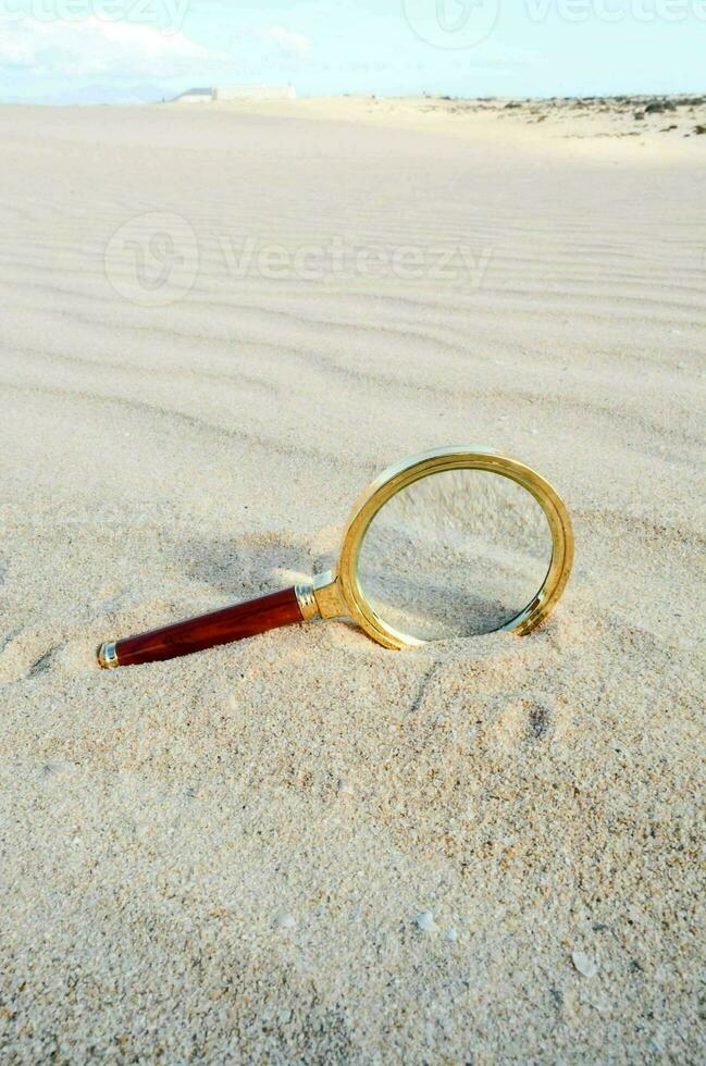 ein Vergrößerung Glas ist Lügen auf das Sand im das Wüste foto