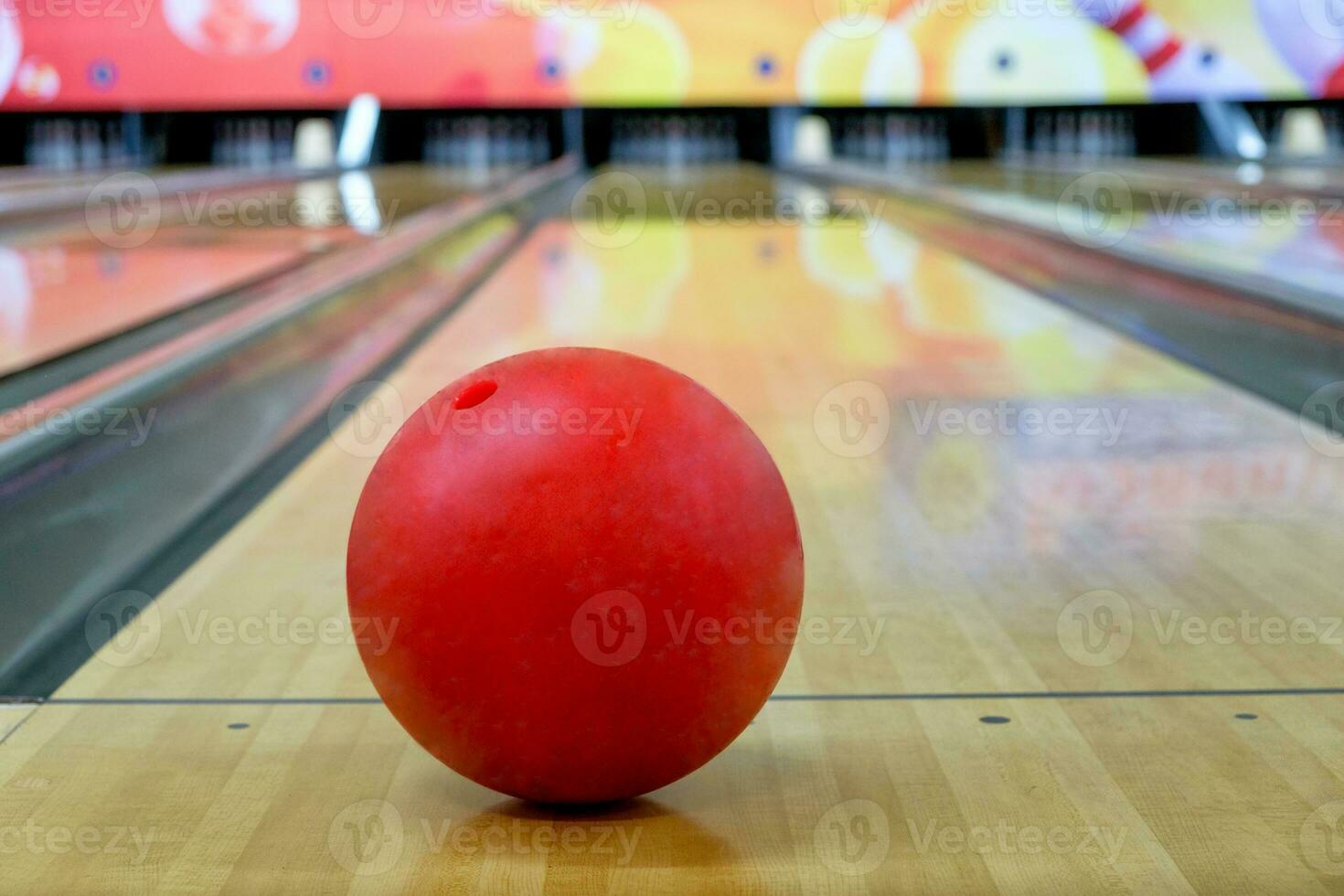 rot Bowling Ball stellen auf Holz Gasse mit verschwommen Bowling Stift foto