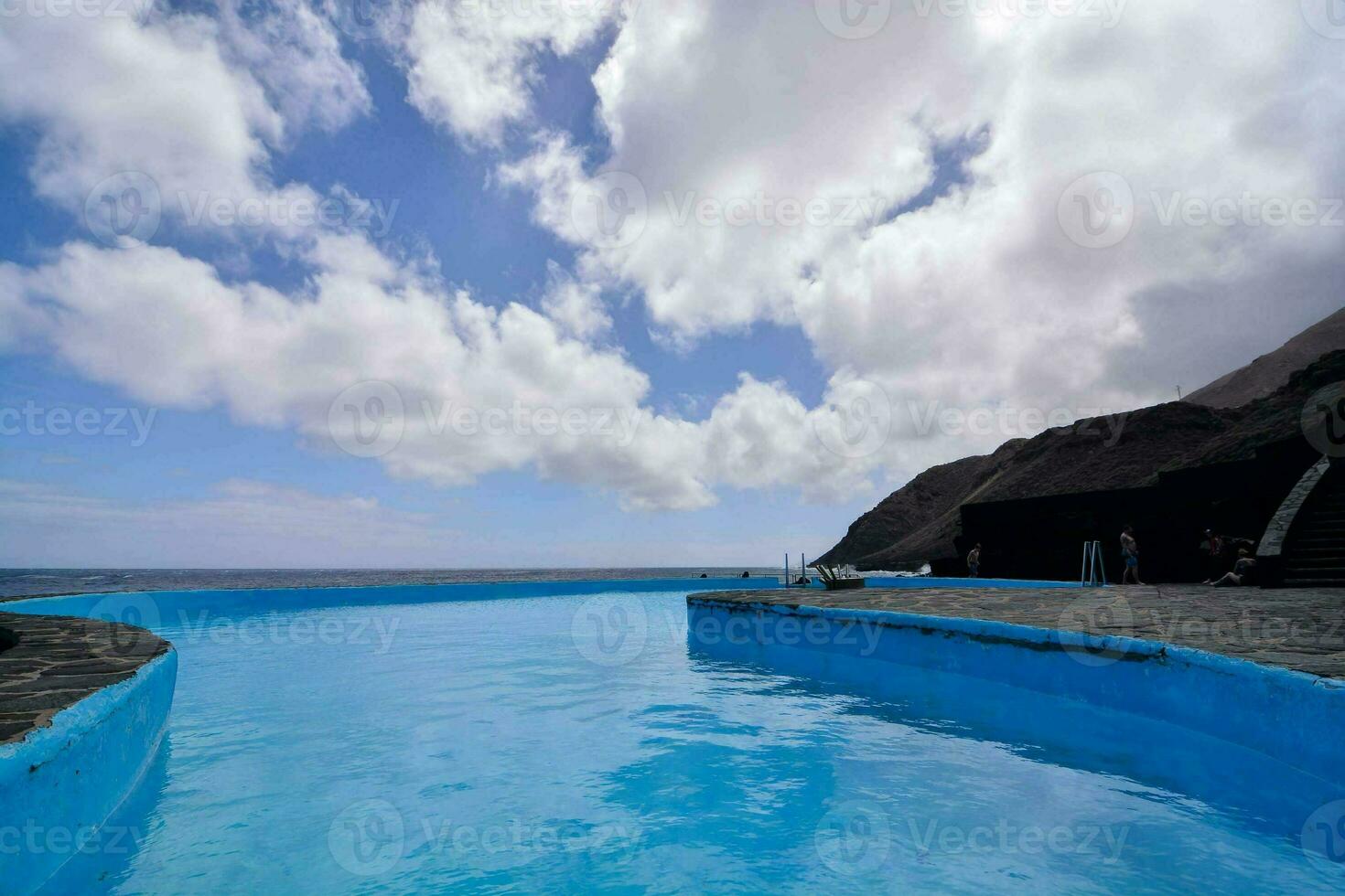 ein Blau Schwimmen Schwimmbad im Vorderseite von ein Cliff foto
