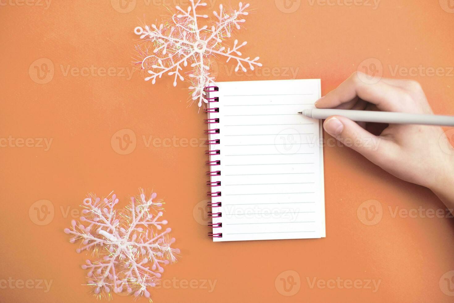 oben Aussicht von Kind Hand mit halten Stift auf Weiß Papier leer Notizbuch und Schreiben Wunsch Liste. foto