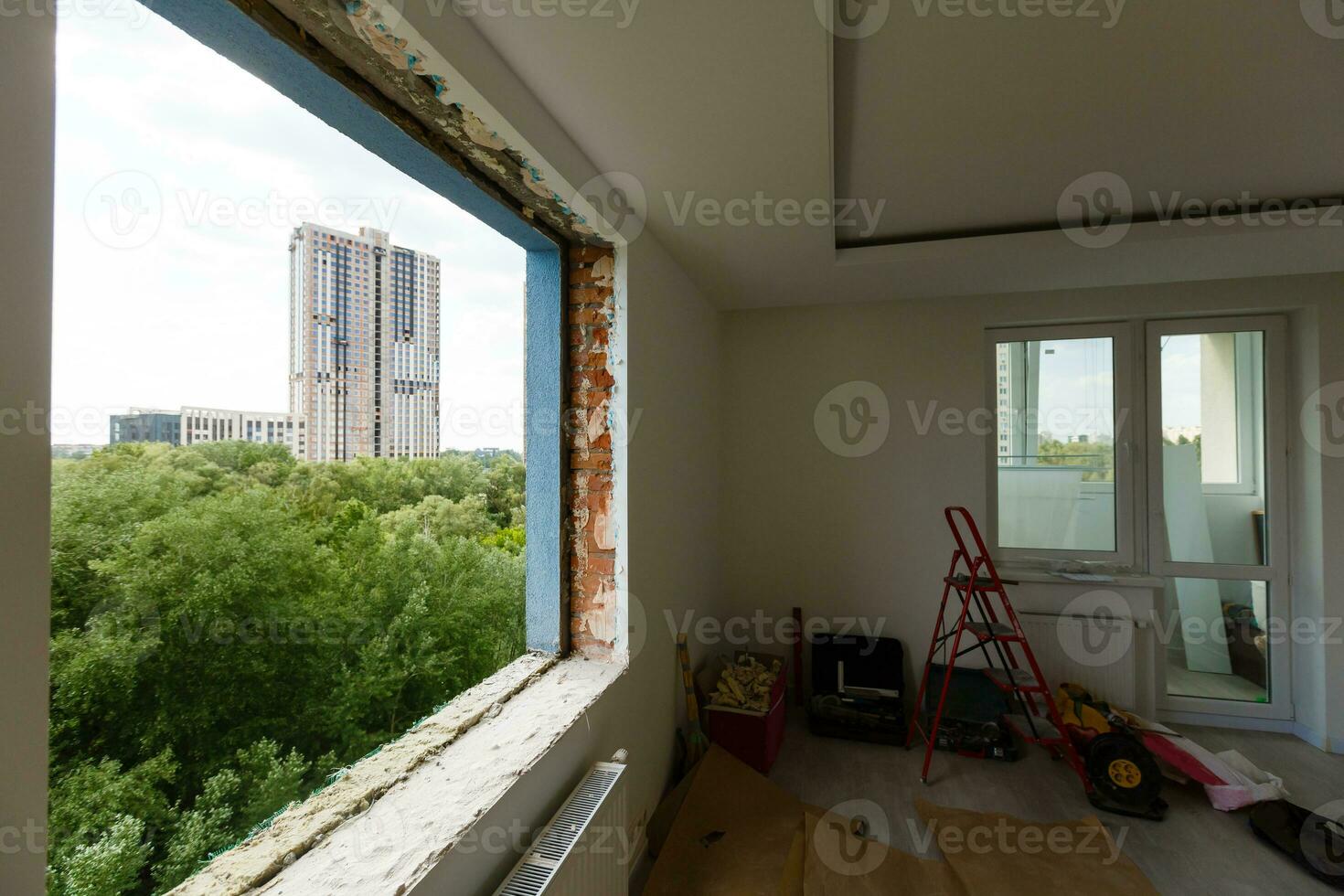 leeren Rahmen auf ein breit Panorama- Fenster. Herrlich Aussicht von das Fenster von ein Wohnung im ein mehrstöckig Gebäude. Dächer von Häuser und Bäume von ein Höhe. schön Aussicht durch das Fenster. Rahmen zum foto