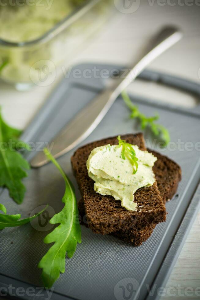 Brot Käse Verbreitung mit Knoblauch und Rucola auf dunkel Brot foto