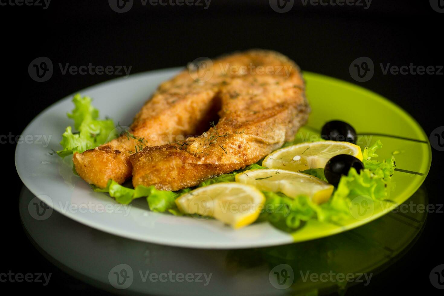 Stück von gebraten Lachs Fisch im ein Teller mit Zitrone foto