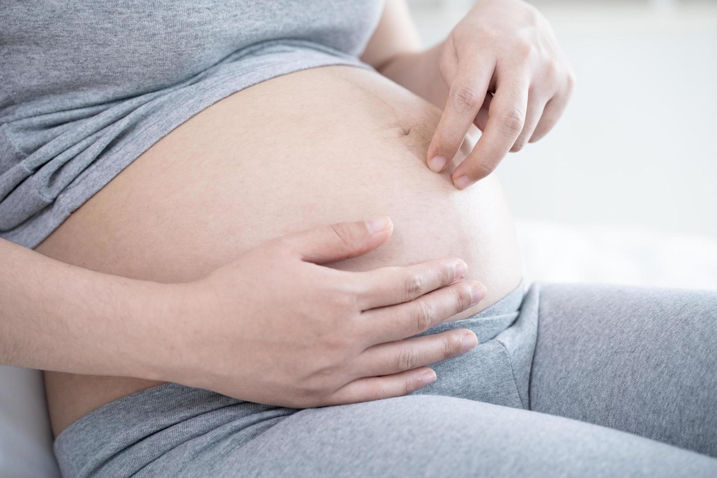 schwangere frau liegt und spielt finger auf ihrem bauch foto
