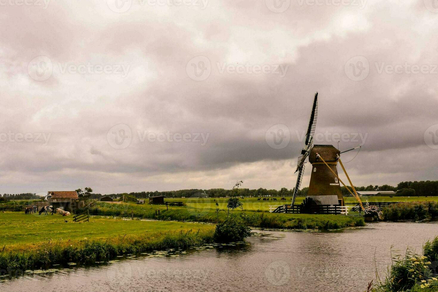 ein Windmühle sitzt auf ein Fluss im ein Feld foto