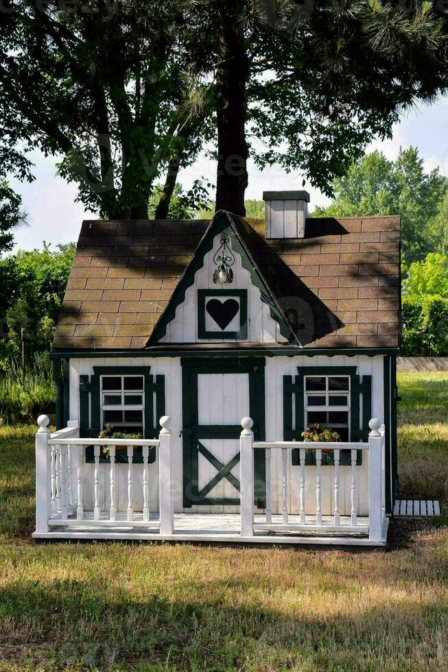 ein klein Weiß und Grün Spielhaus mit ein Veranda foto