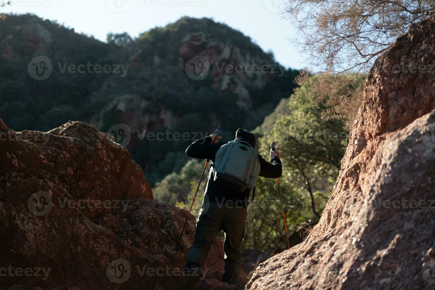 mittleren Alters Mann klettert das Berg im das garraf natürlich Park, unterstützt durch Wandern Stangen. foto