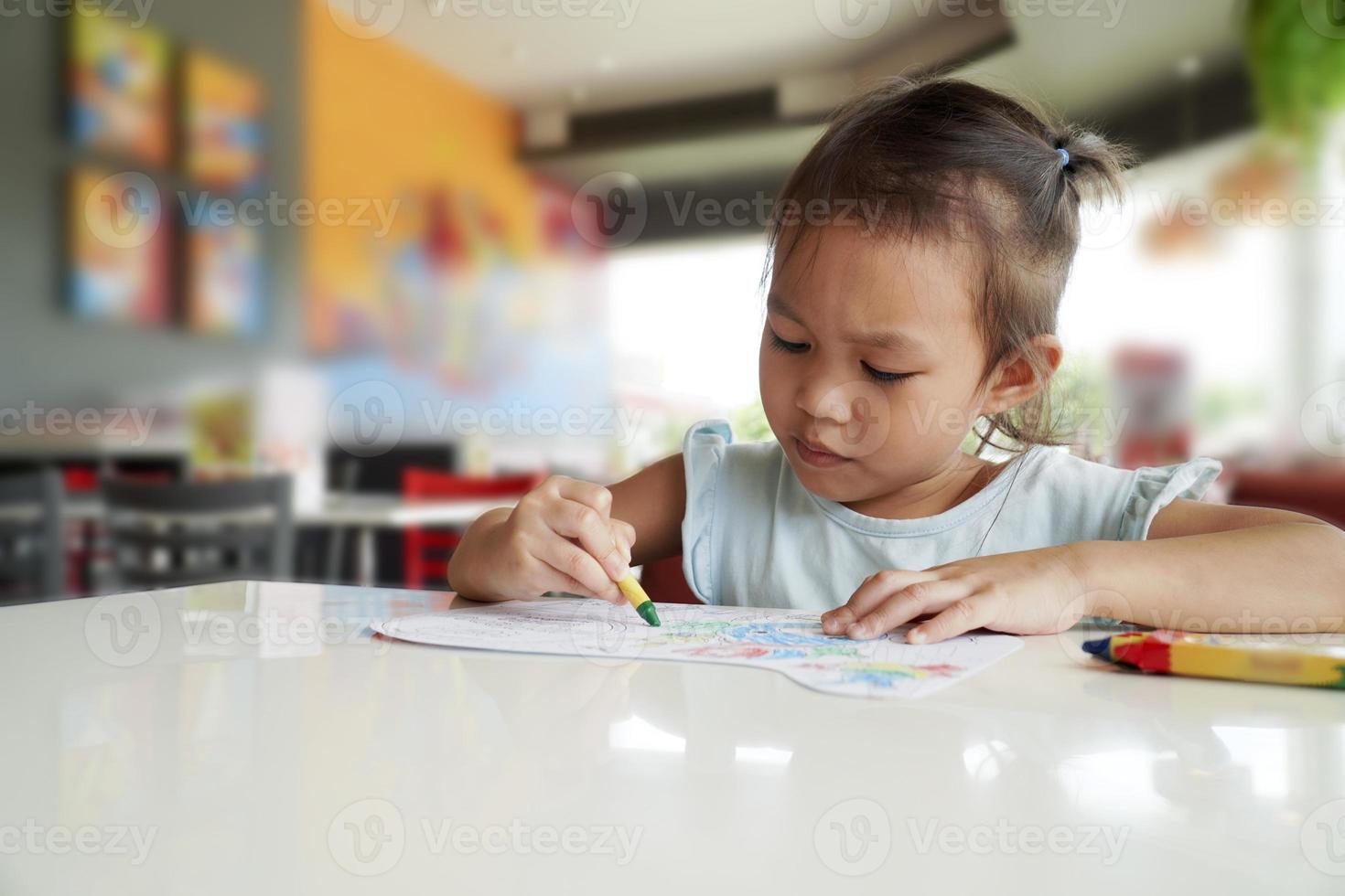 kleines Kind beabsichtigt, im Klassenzimmer mit Buntstiften auszumalen foto