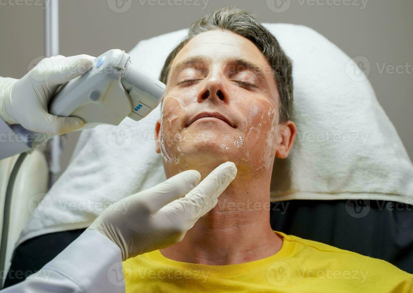nahaufnahme schöner mann mit farblichttherapie zur stimulierung der gesichtshaut durch professionelle kosmetologen wohlbefinden. foto