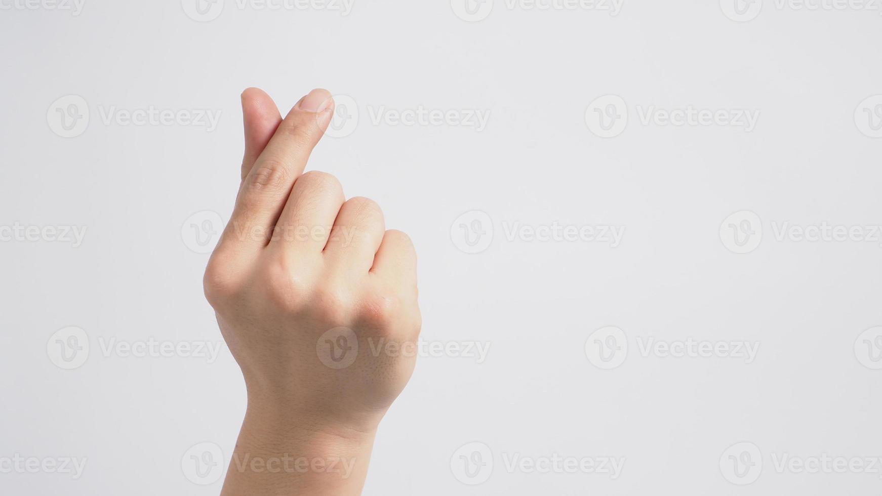 männliches Model macht Mini-Herz-Handzeichen mit Rückhand auf weißem Hintergrund. foto