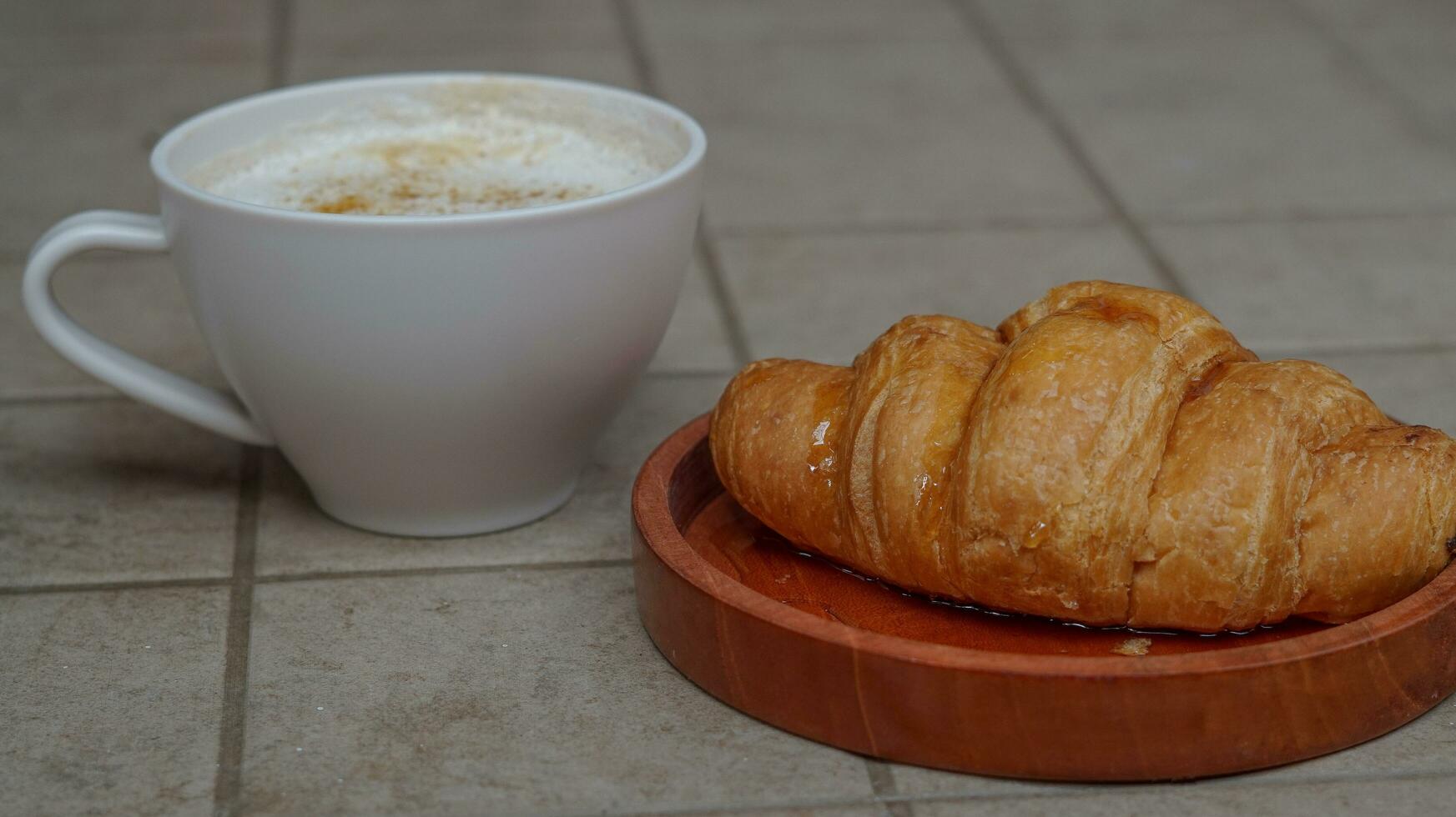 Croissant gekrönt mit Honig mit ein Glas von Kaffee Latté foto