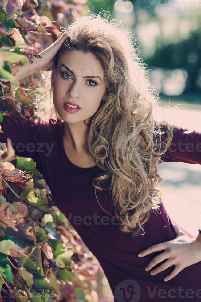 junge Frau mit langen blonden Locken im städtischen Hintergrund foto