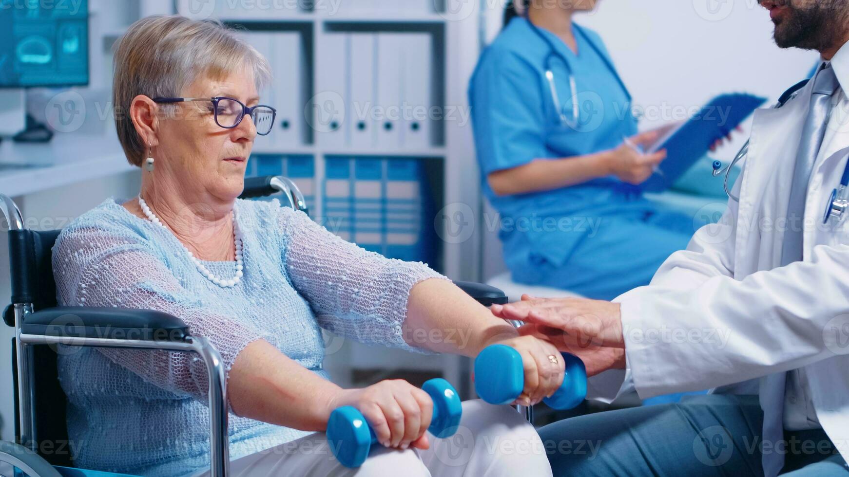 Physiotherapie zum Alten Frau im Rollstuhl, sie ist üben mit Hanteln zu genesen nach ein muschel Trauma. modern Privat Krankenhaus oder Rehabilitation Klinik. Heben Übung zum deaktiviert Menschen foto