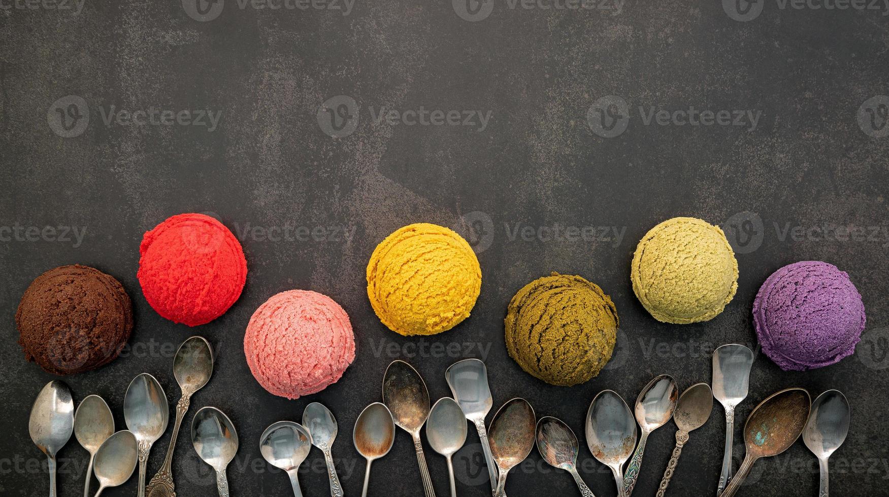 Verschiedene Eissorten mit Blaubeer-, Pistazien-, Mandel-, Orangen-, Grüntee- und Schokoladen-Setup auf dunklem Steinhintergrund. Sommer und süßes Menükonzept. foto