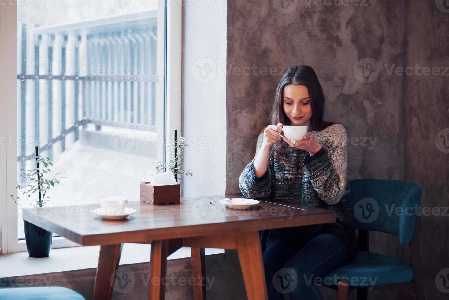 lächelnde Frau im Café mit Handy und SMS in sozialen Netzwerken, allein sitzend foto