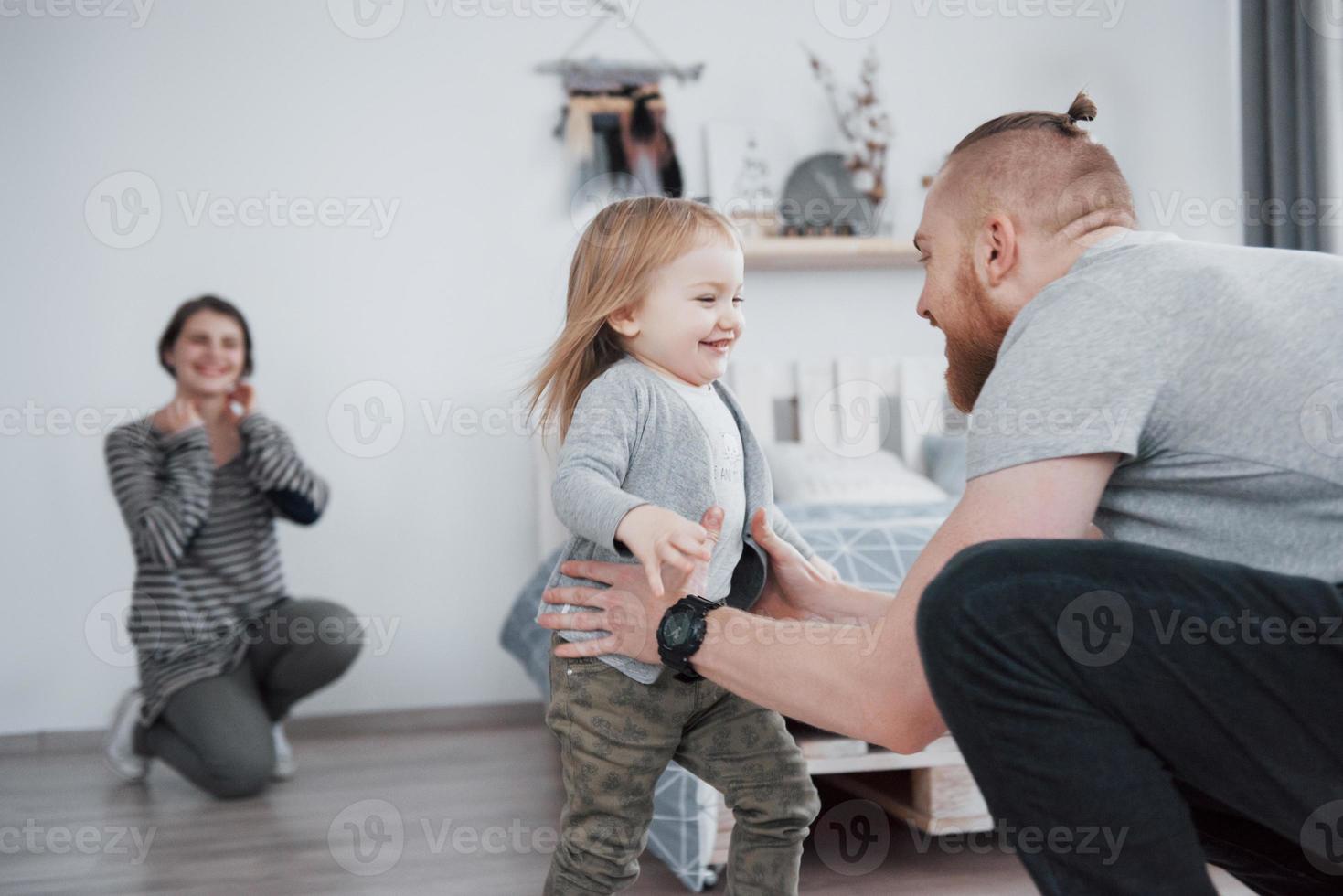 glückliche Familie hat Spaß zu Hause. Mutter, Vater und kleine Tochter mit Plüschtier genießen das Zusammensein foto