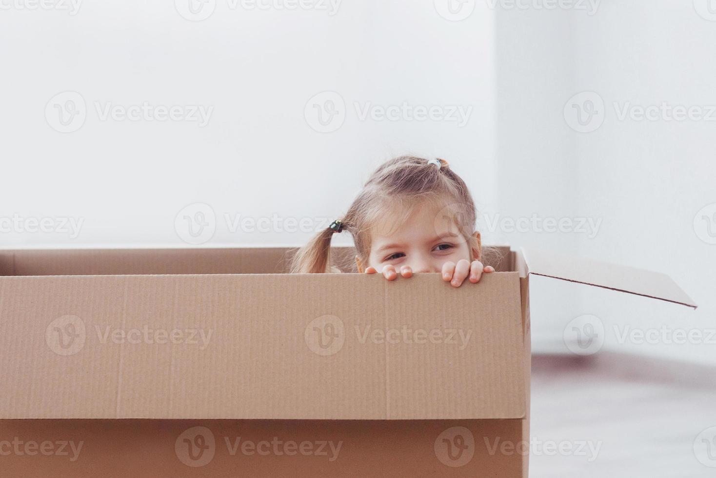 Kind im Vorschulalter, das in der Papierbox spielt. Kindheit, Reparaturen und neues Hauskonzept foto
