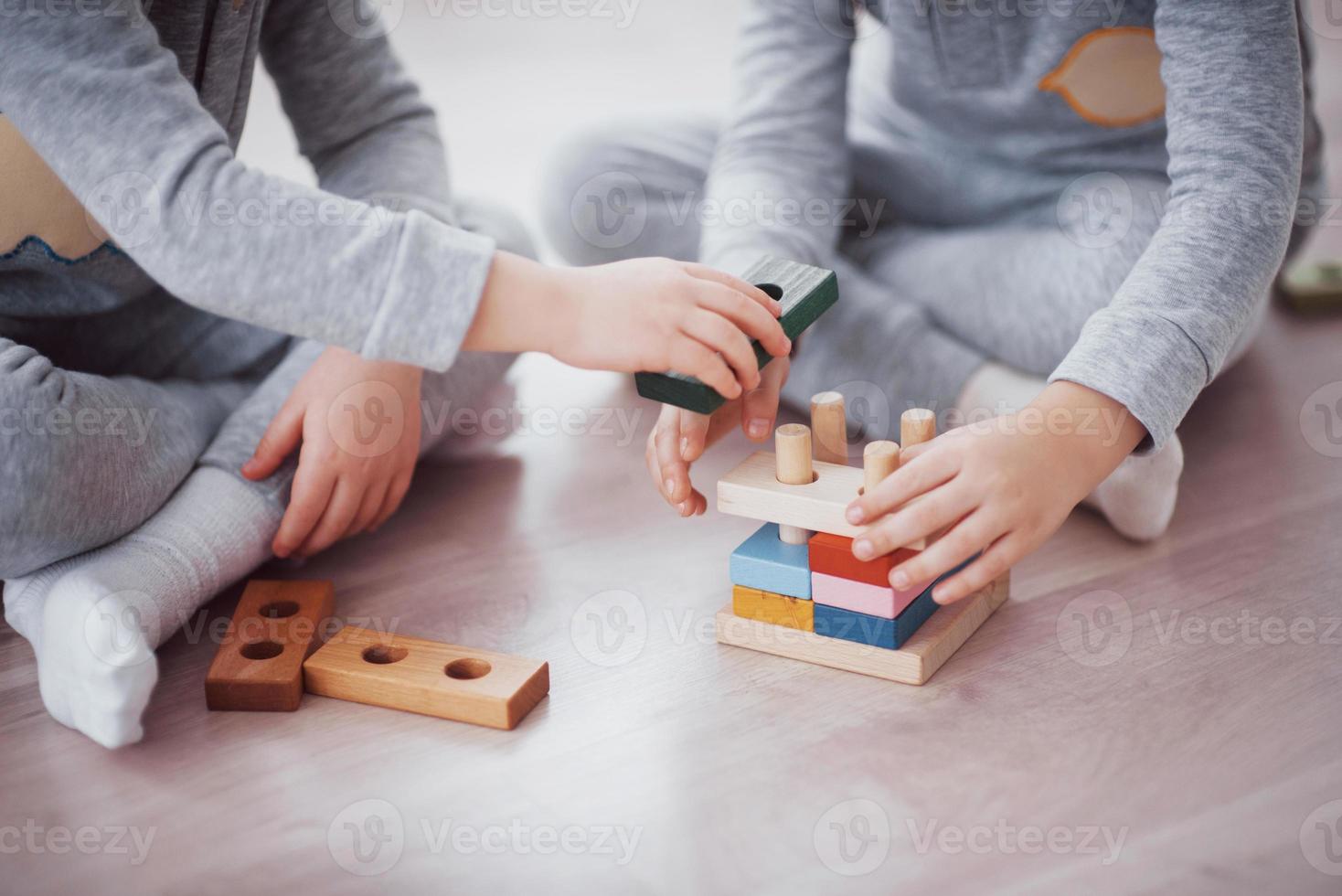 Kinder spielen mit einem Spielzeugdesigner auf dem Boden des Kinderzimmers. zwei Kinder spielen mit bunten Blöcken. Lernspiele im Kindergarten foto