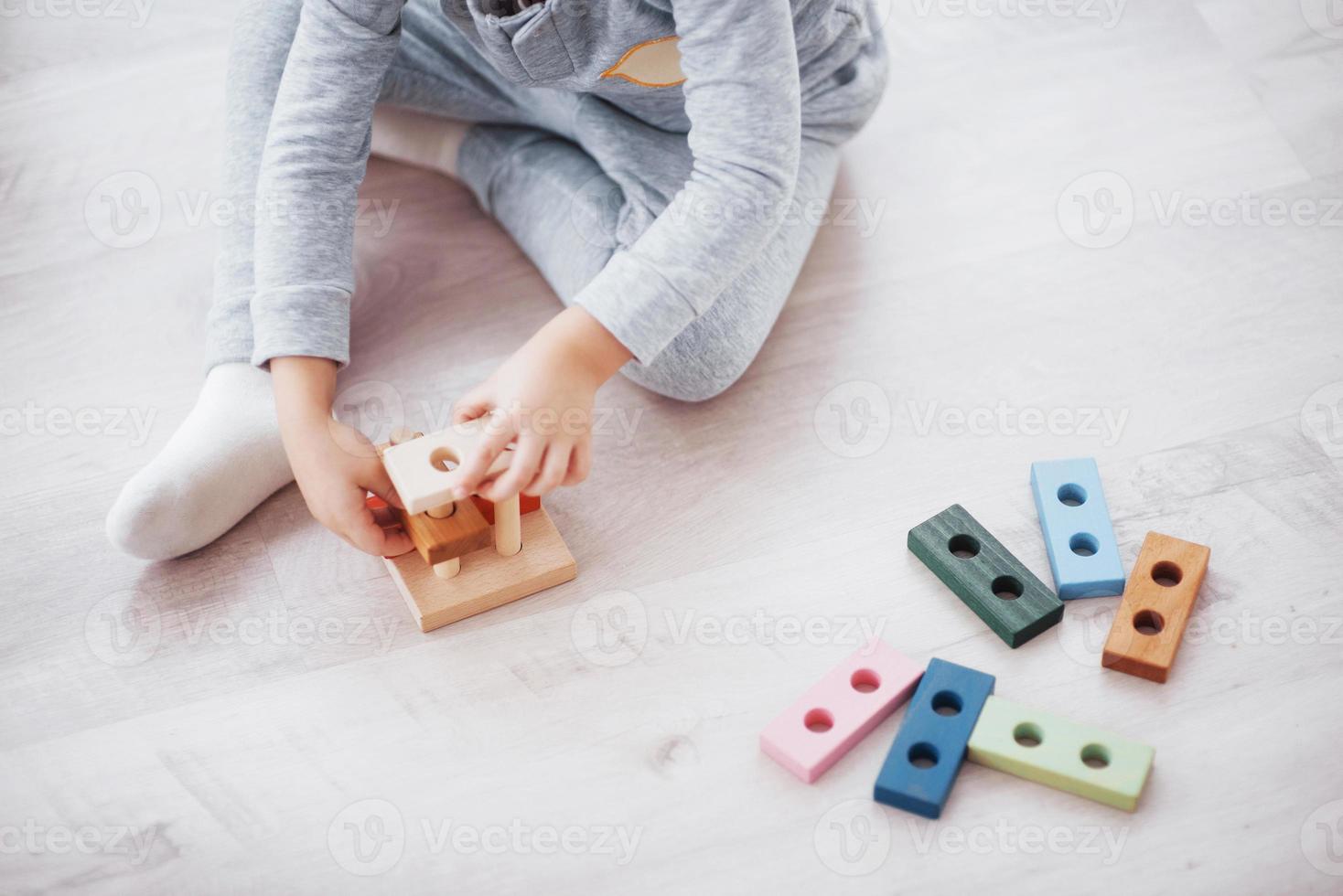 Kinder spielen mit einem Spielzeugdesigner auf dem Boden des Kinderzimmers. zwei Kinder spielen mit bunten Blöcken. Lernspiele im Kindergarten foto