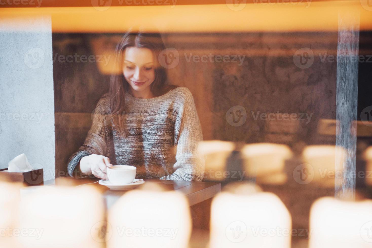 lächelnde Frau im Café mit Handy und SMS in sozialen Netzwerken, allein sitzend foto
