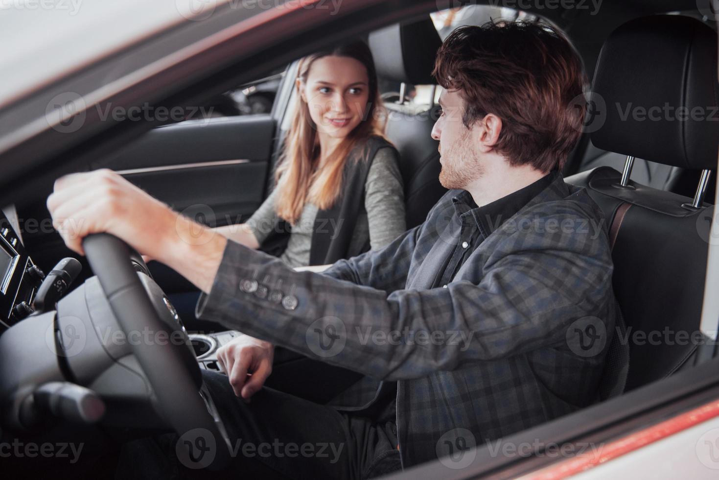 Gut aussehender reifer Mann, der seine Frau anlächelt und Musik anmacht, während er zusammen in ihrem neuen Auto sitzt foto