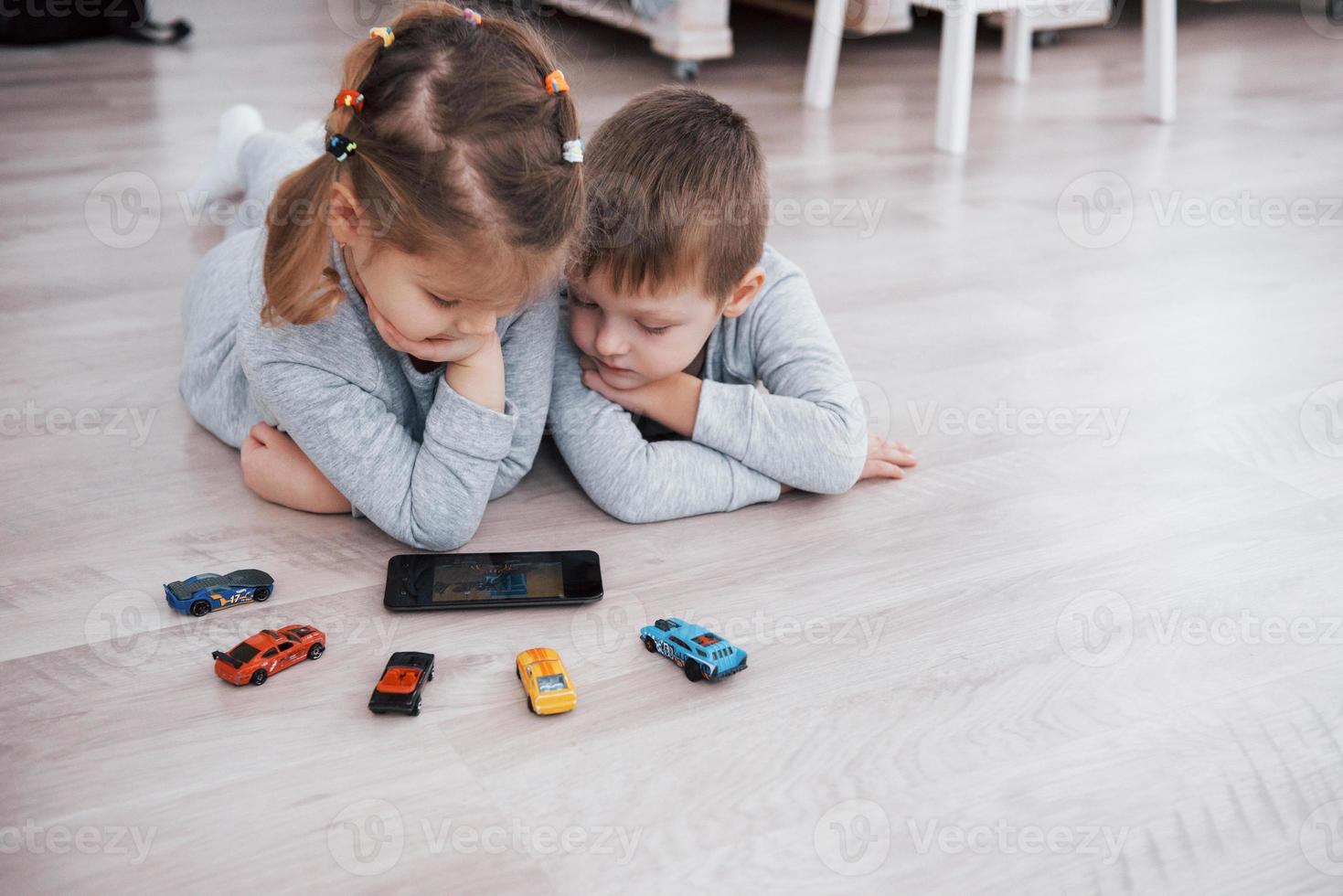 Kinder, die zu Hause digitale Geräte verwenden. Bruder und Schwester im Pyjama schauen sich Cartoons an und spielen Spiele auf ihrem Technologie-Tablet foto