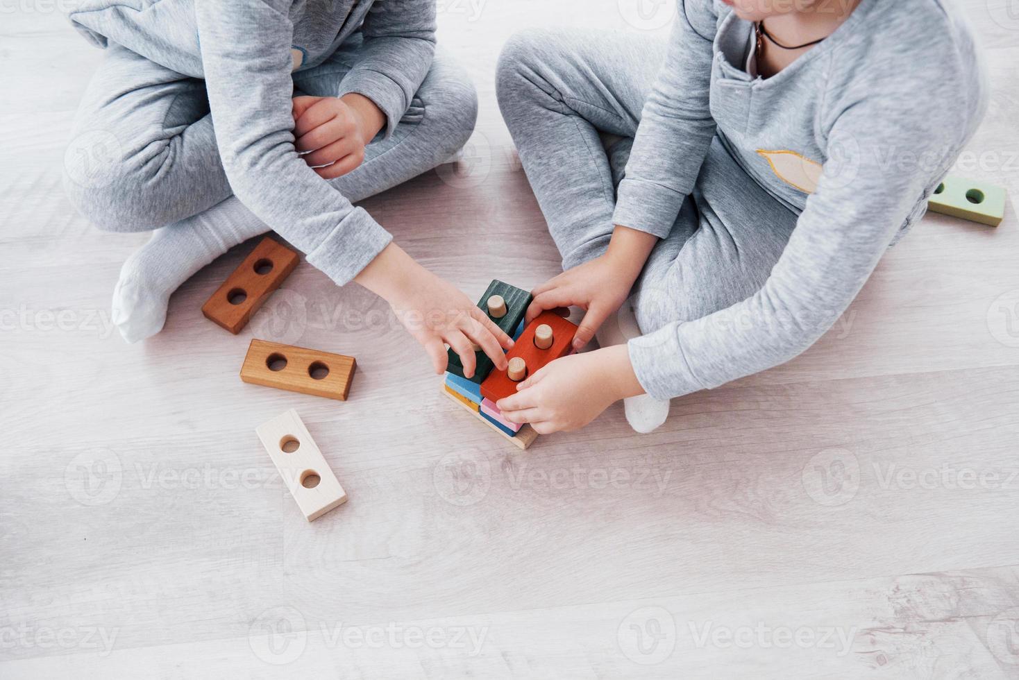 Kinder spielen mit einem Spielzeugdesigner auf dem Boden des Kinderzimmers. zwei Kinder spielen mit bunten Blöcken. Lernspiele im Kindergarten foto