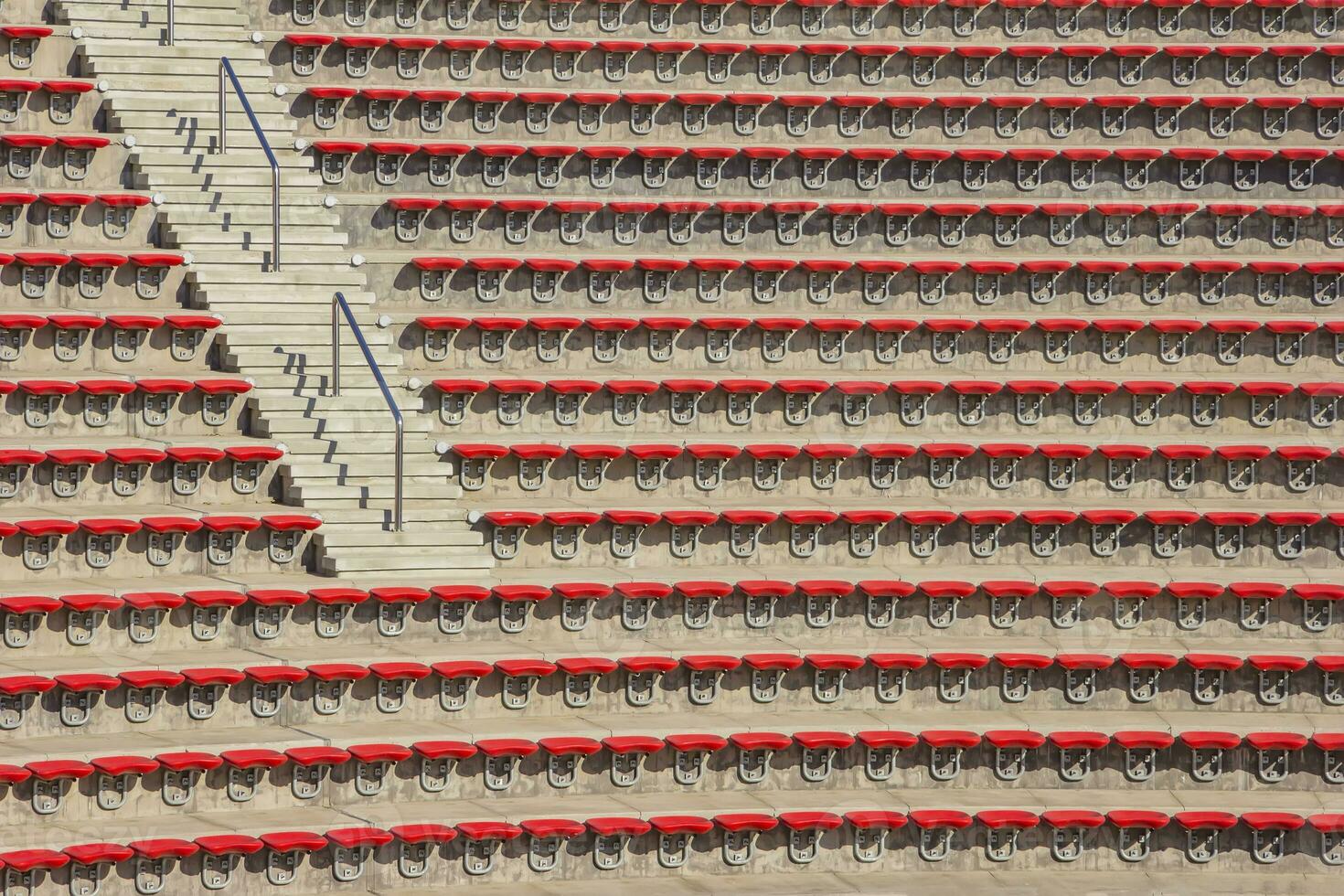 leere rote Plastikstühle auf den Tribünen des Stadions oder Amphitheaters. viele leere Zuschauerplätze auf den Tribünen. foto