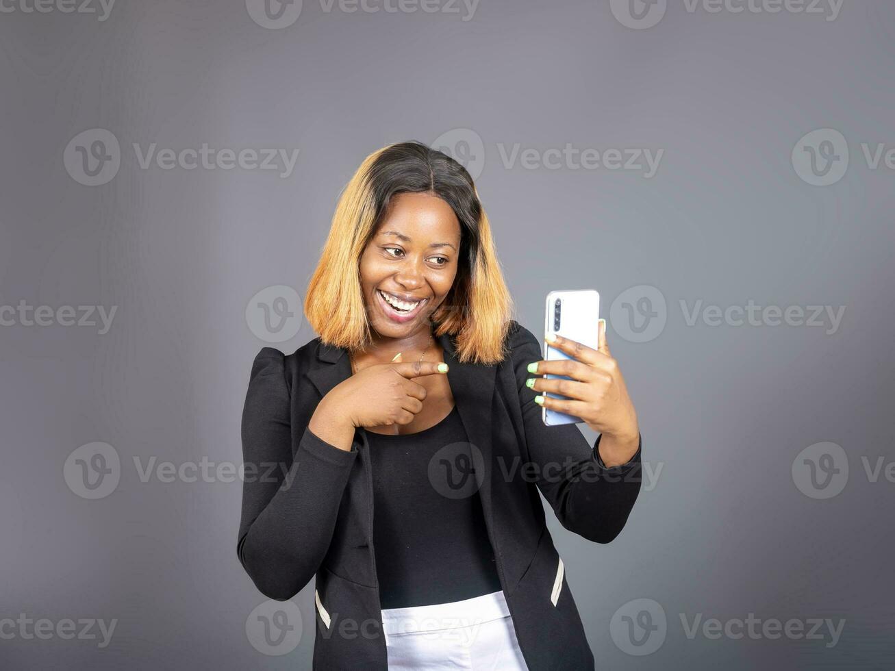 schwarz afrikanisch Frau mit Clever Telefon Stand Über ein Studio Mauer foto