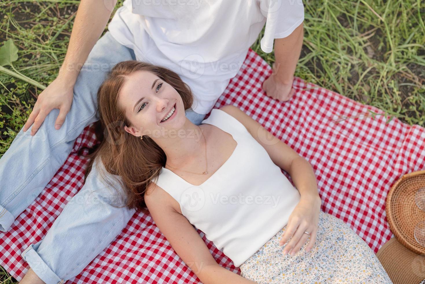 junges Paar beim Picknick auf Sonnenblumenfeld bei Sonnenuntergang foto