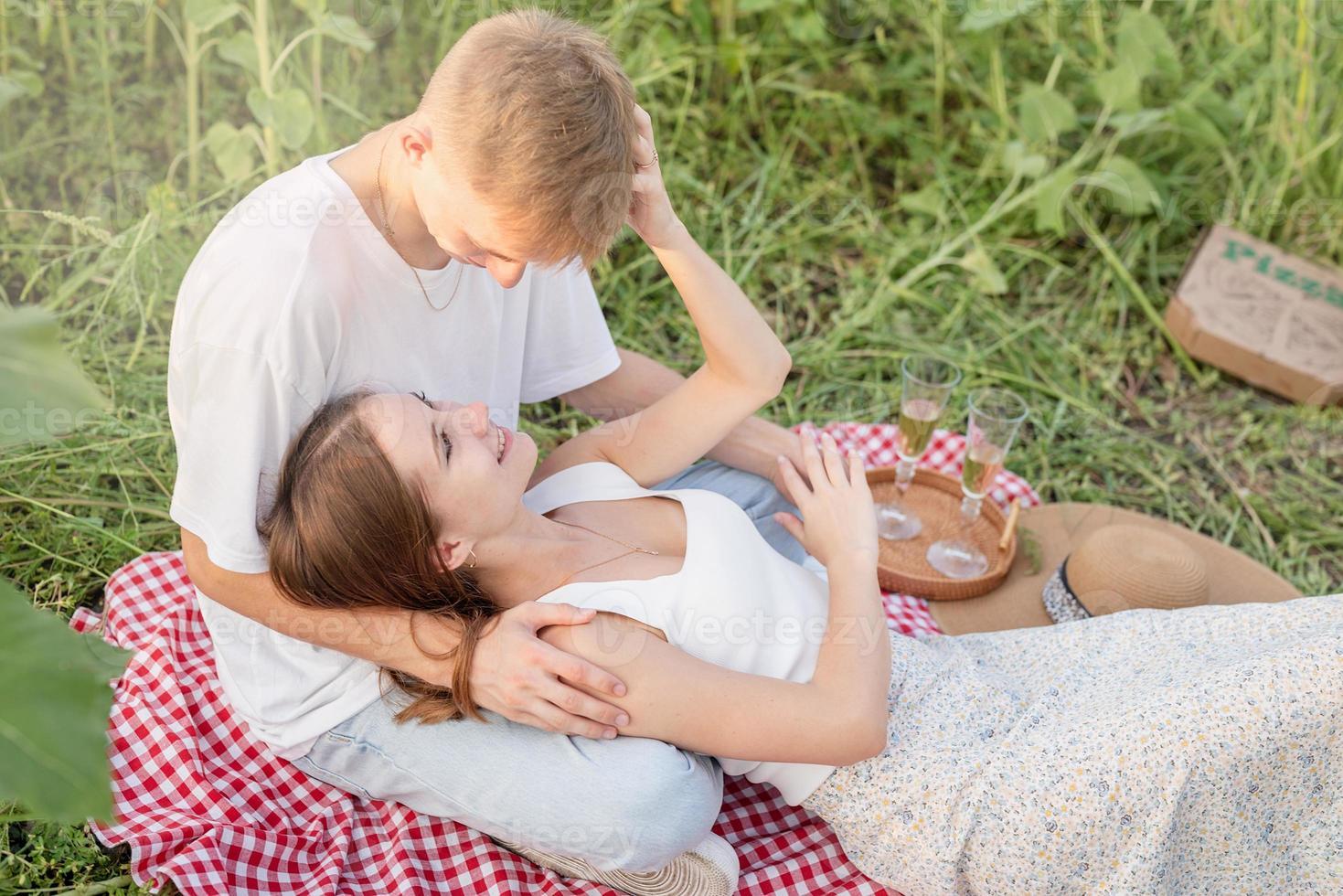 junges Paar beim Picknick auf Sonnenblumenfeld bei Sonnenuntergang foto