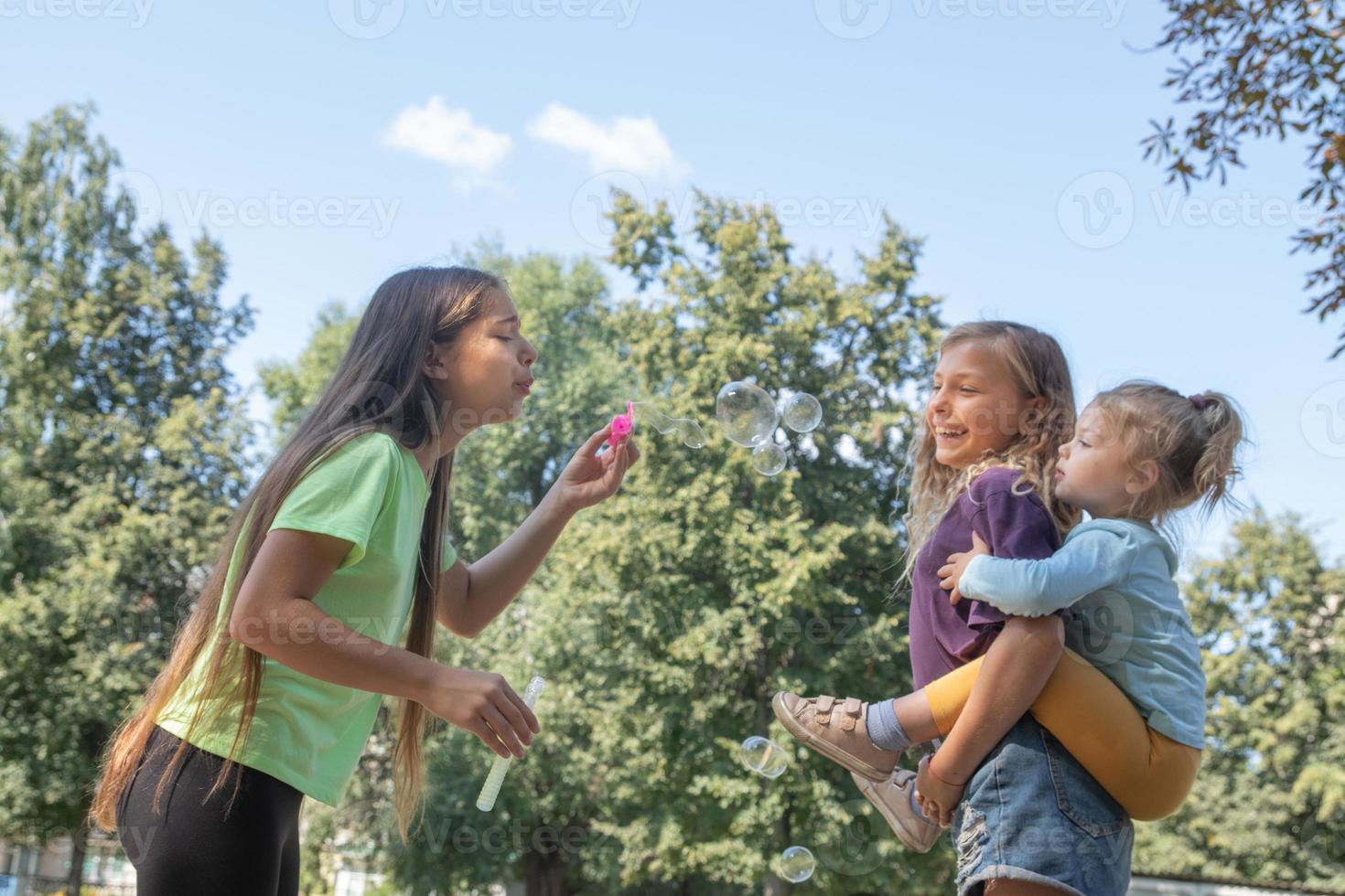 Mädchen spielen draußen mit Seifenblasen. Kindheit und Spaßkonzept foto