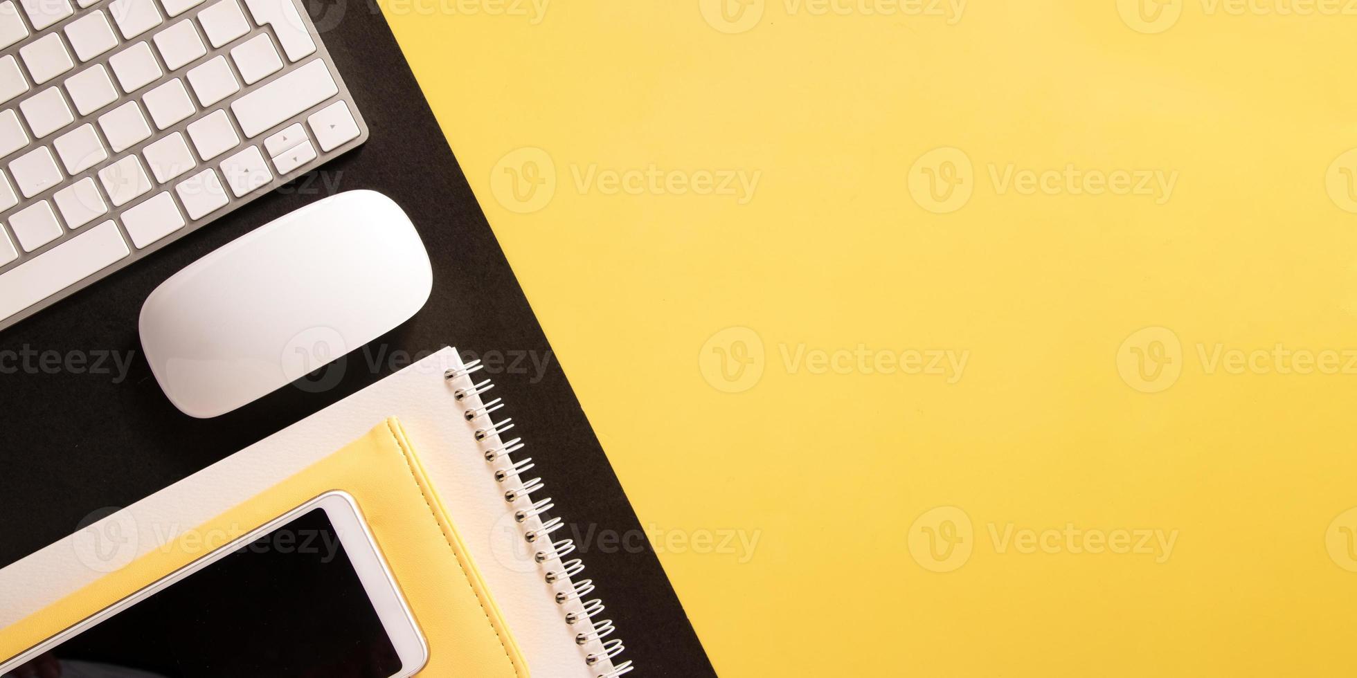 Flacher Desktop mit Tastatur, Telefon, Notizblock mit Kopienraum auf farbigem Hintergrund im Bannerformat foto