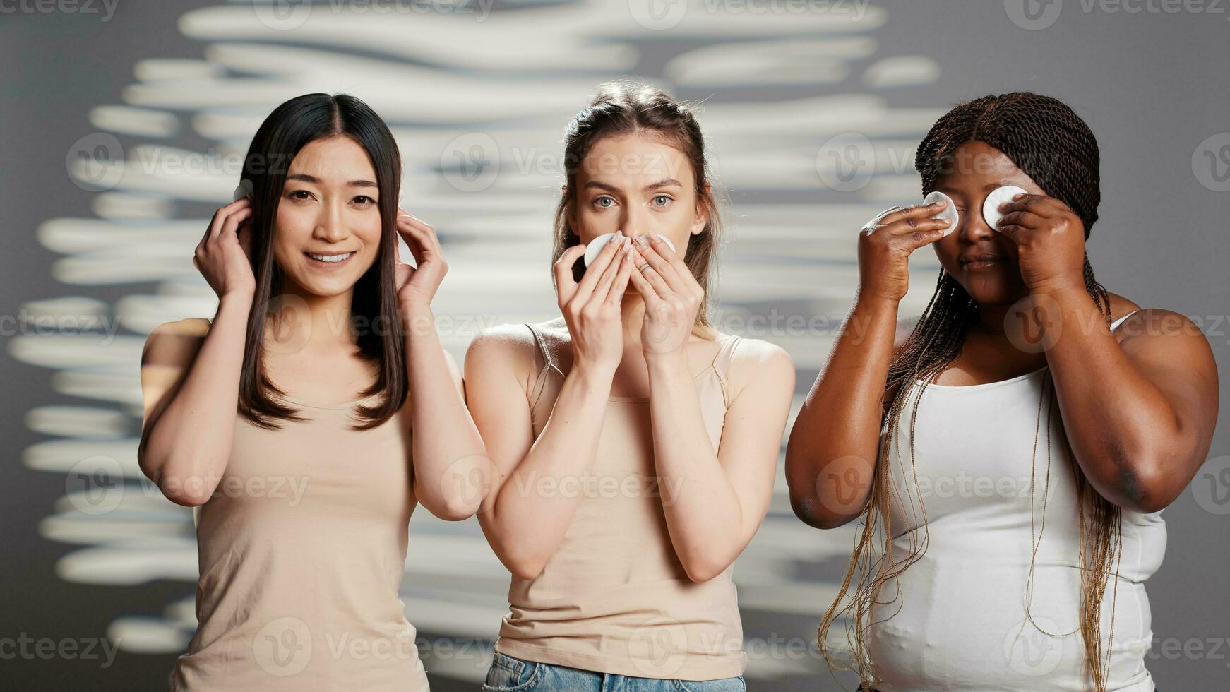 jung Modelle tun drei weise Affen Zeichen mit Baumwolle Pads, Erstellen Schönheit Hautpflege Kampagne im Studio. vielfältig Frauen haben Spaß spielen um mit Kosmetika, Reinigung Haut. foto