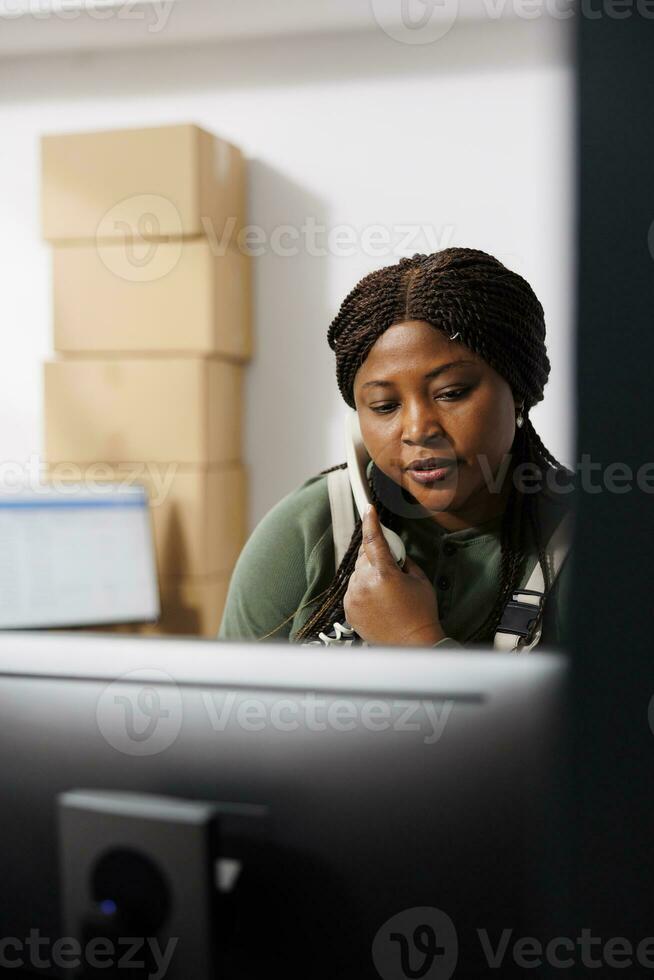 afrikanisch amerikanisch Manager Stehen beim Zähler Schreibtisch reden mit Fernbedienung Klient mit Festnetz Telefon, diskutieren bestellen Logistik. Lager Mitarbeiter Arbeiten beim Fan-Shop Inventar im Warenhaus foto