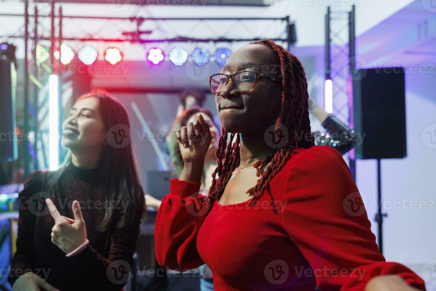 afrikanisch amerikanisch Frau Party machen auf Tanzfläche während entspannend im Nachtclub. jung sorglos Mädchen Tanzen und genießen Nachtleben Unterhaltung beim Diskothek im überfüllt Verein foto