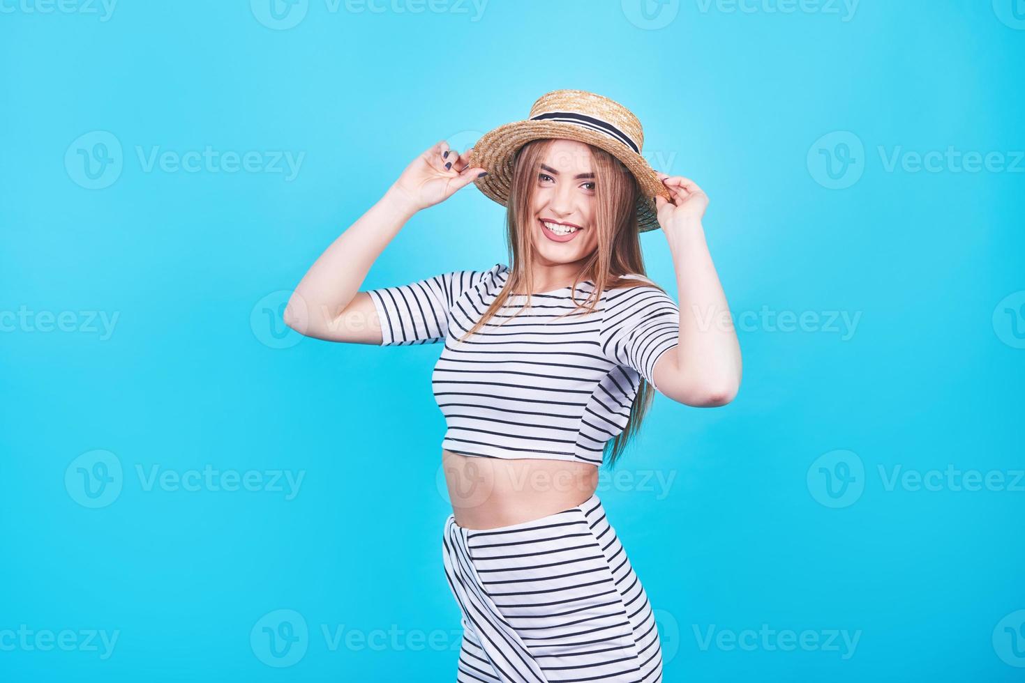 attraktives mädchen in weißen und schwarzen streifen, hut, sonnenbrille, emotional geöffneter mund auf hellblauem hintergrund mit perfektem körper. isoliert. Studioaufnahme foto