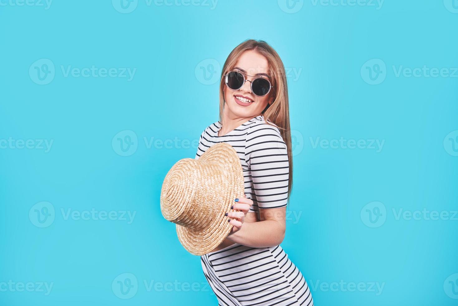 attraktives mädchen in weißen und schwarzen streifen, hut, sonnenbrille, emotional geöffneter mund auf hellblauem hintergrund mit perfektem körper. isoliert. Studioaufnahme foto