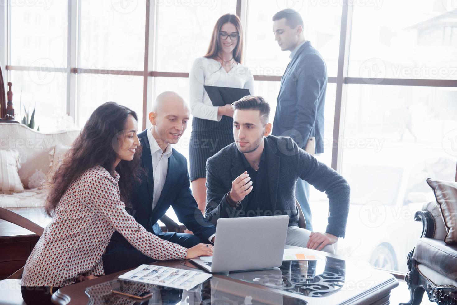 Junges Team von Mitarbeitern, die großartige Geschäftsgespräche im modernen Coworking-Büro führen. Teamwork-Menschen-Konzept foto