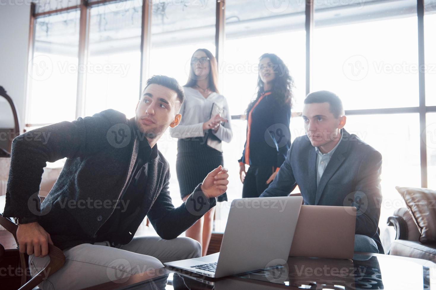 Junges Team von Mitarbeitern, die großartige Geschäftsgespräche im modernen Coworking-Büro führen. Teamwork-Menschen-Konzept foto
