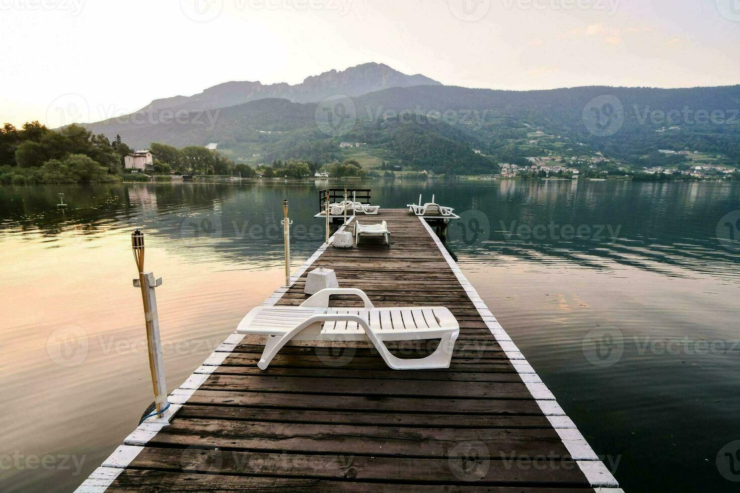 ein hölzern Dock mit Stühle und ein Berg im das Hintergrund foto