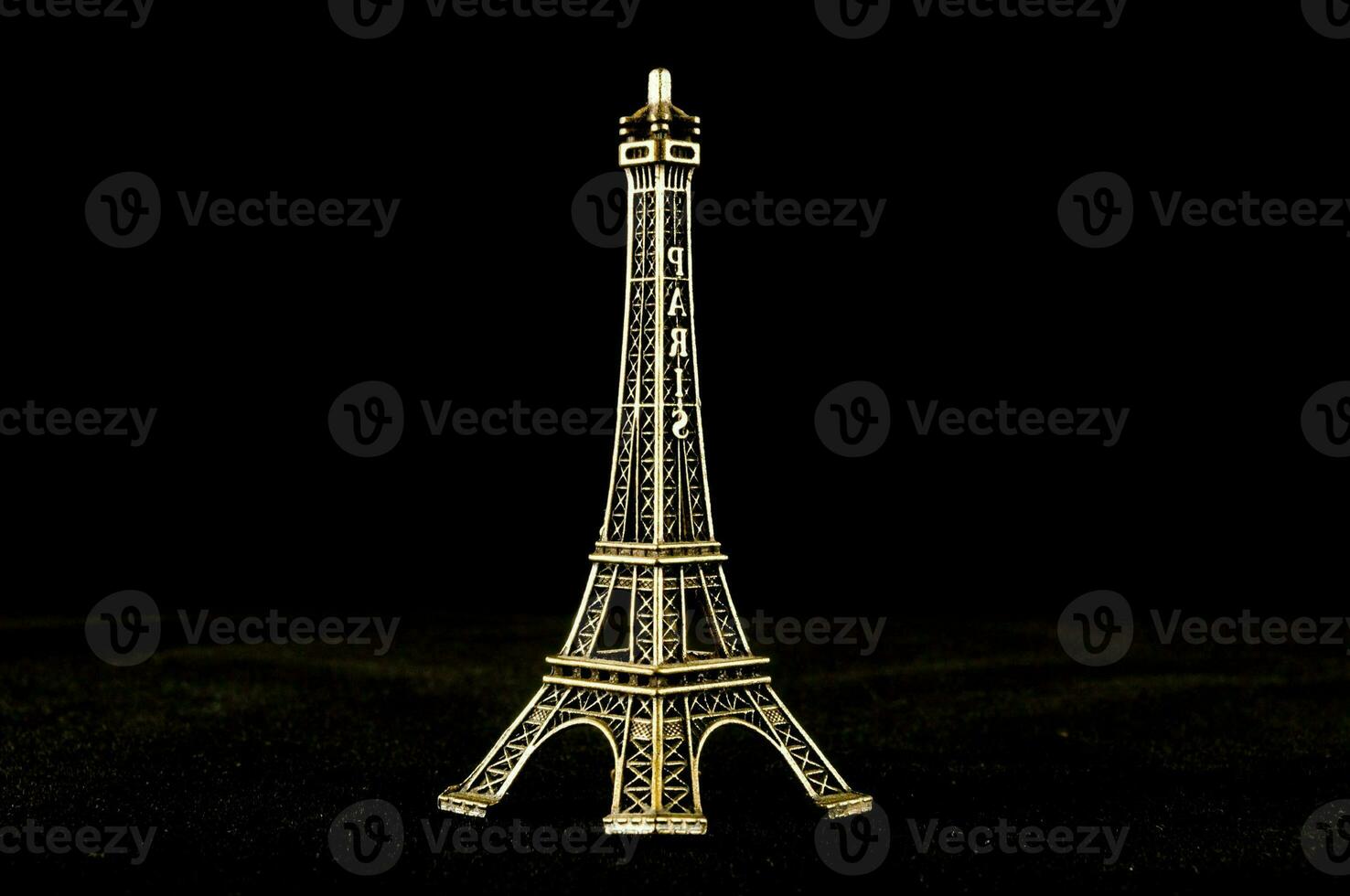 ein Gold Eiffel Turm auf ein schwarz Hintergrund foto