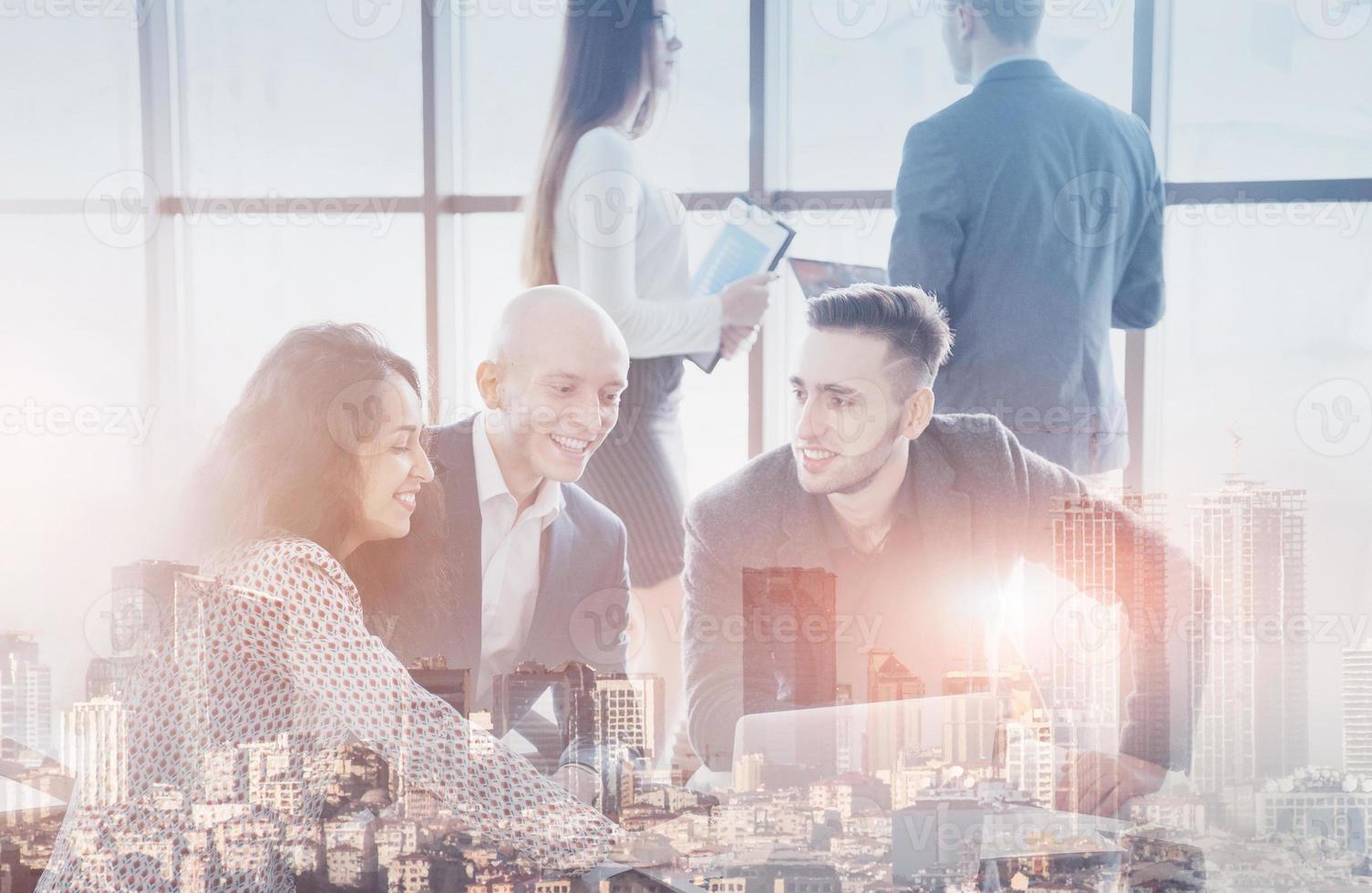 Junges Team von Mitarbeitern, die großartige Geschäftsgespräche im modernen Coworking-Büro führen. Teamwork-Menschen-Konzept. Doppelausstellung, Panorama der modernen Stadt foto