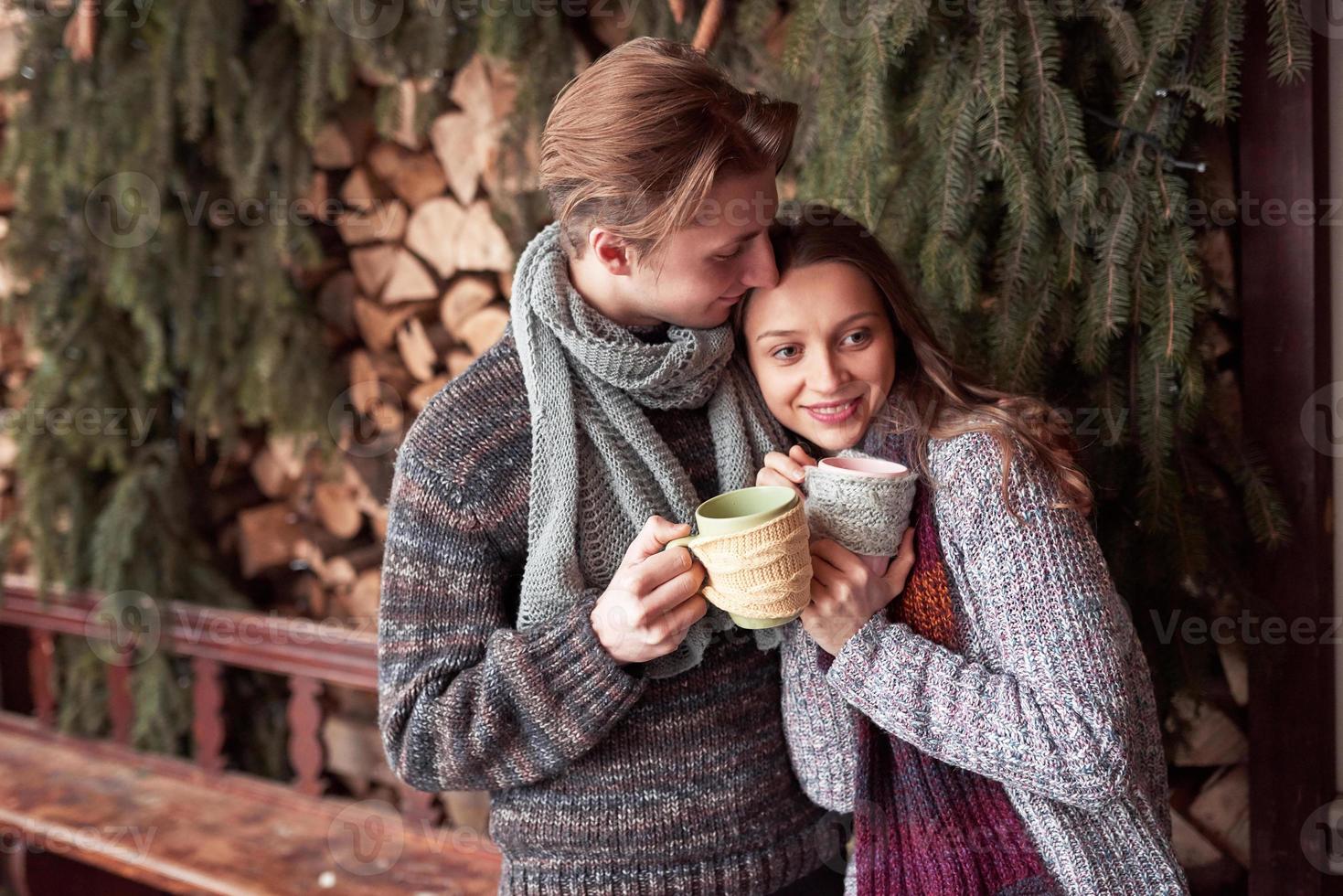 junges Paar, das im Winter in einer romantischen Hütte im Freien frühstückt. Winterurlaub und Urlaub. Weihnachtspaare des glücklichen Mannes und der Frau trinken heißen Wein. verliebtes Pärchen foto