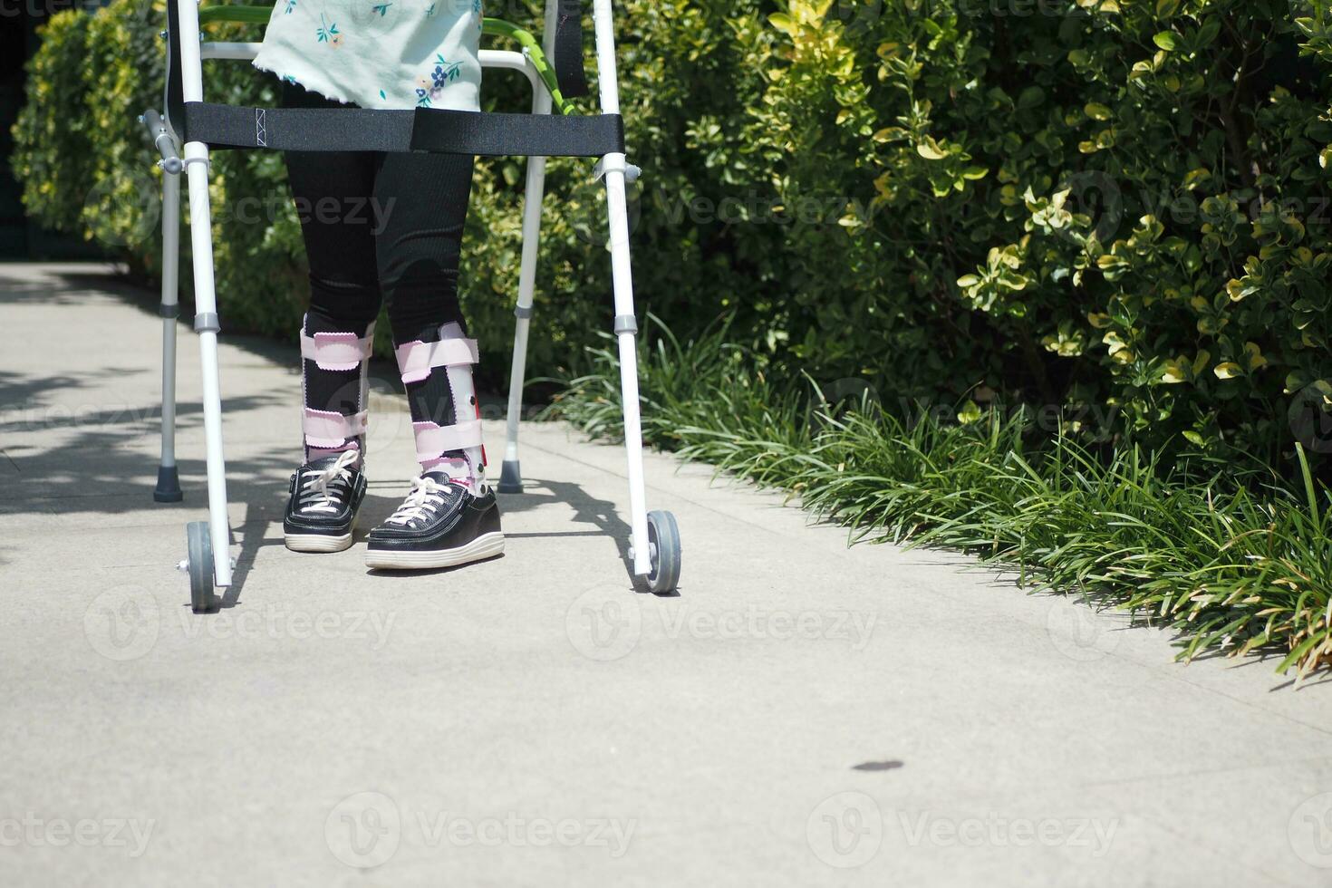 Kind mit Gehen Rahmen und Knie Orthese draussen foto