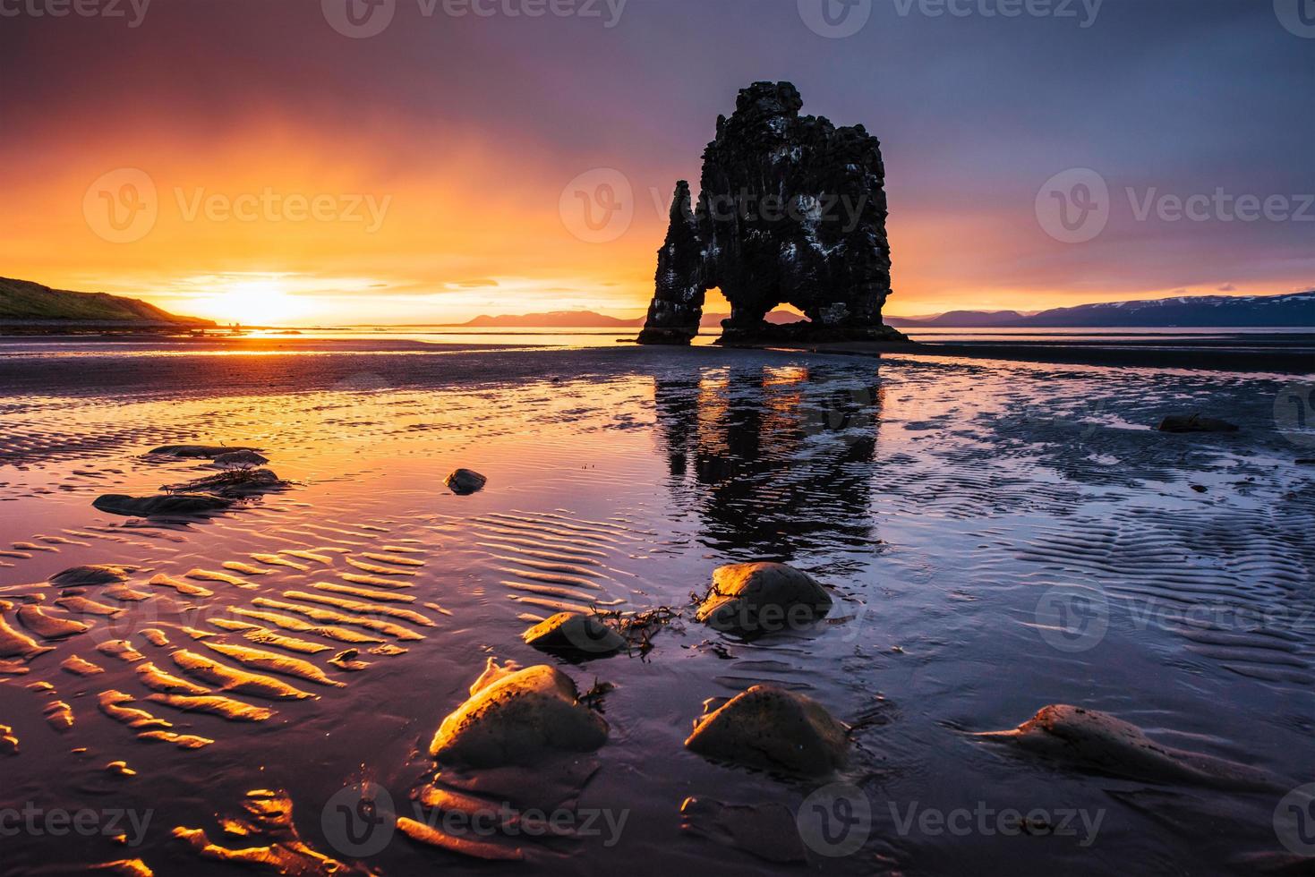 hvitserkur ist ein spektakulärer Felsen im Meer an der Nordküste Islands. Legenden sagen, es sei ein versteinerter Troll. Auf diesem Foto spiegelt sich die Hvitserkur nach dem Mitternachtssonnenuntergang im Meerwasser