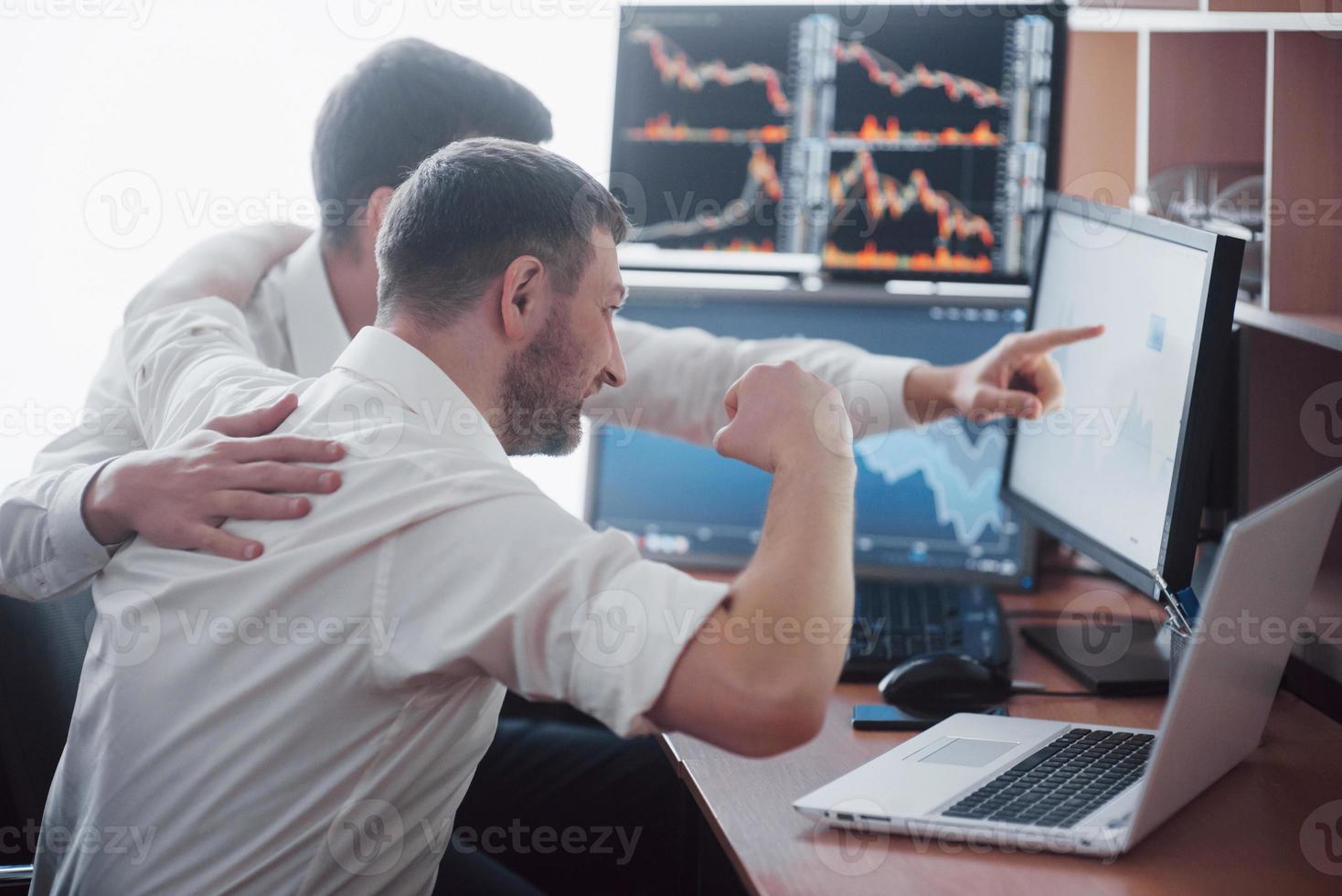 Ein Team von Börsenmaklern unterhält sich in einem dunklen Büro mit Bildschirmen. Analyse von Daten, Grafiken und Berichten für Anlagezwecke. Kreative Teamwork-Händler foto