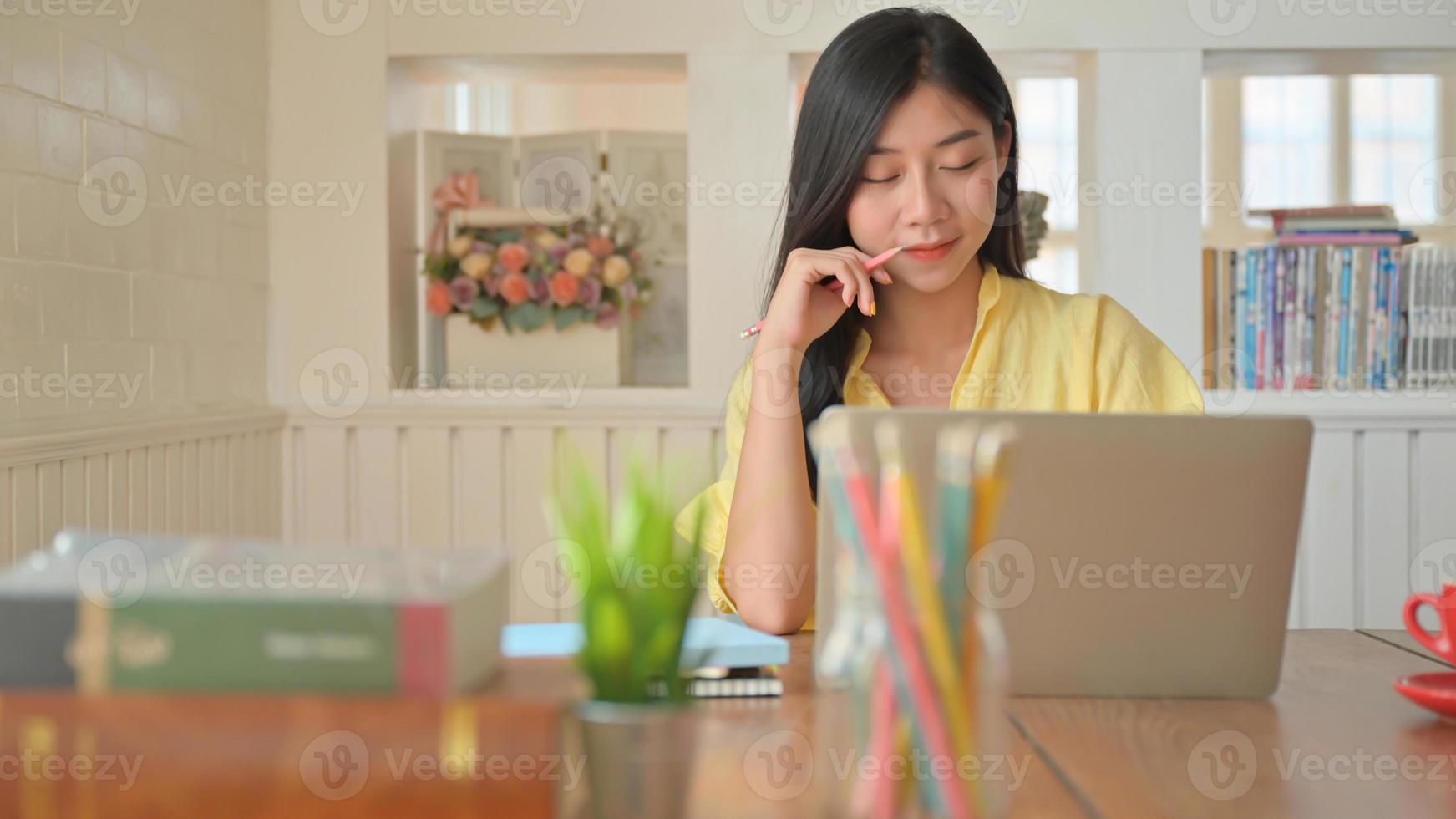 eine junge frau benutzt einen laptop für die arbeit, sie arbeitet von zu hause und ist müde. foto